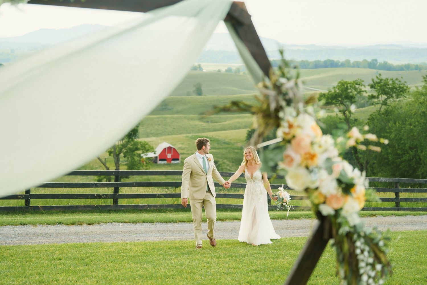 Bride and Groom hold hands and walk through fields at Serenity Hill Farm in West Virginia.