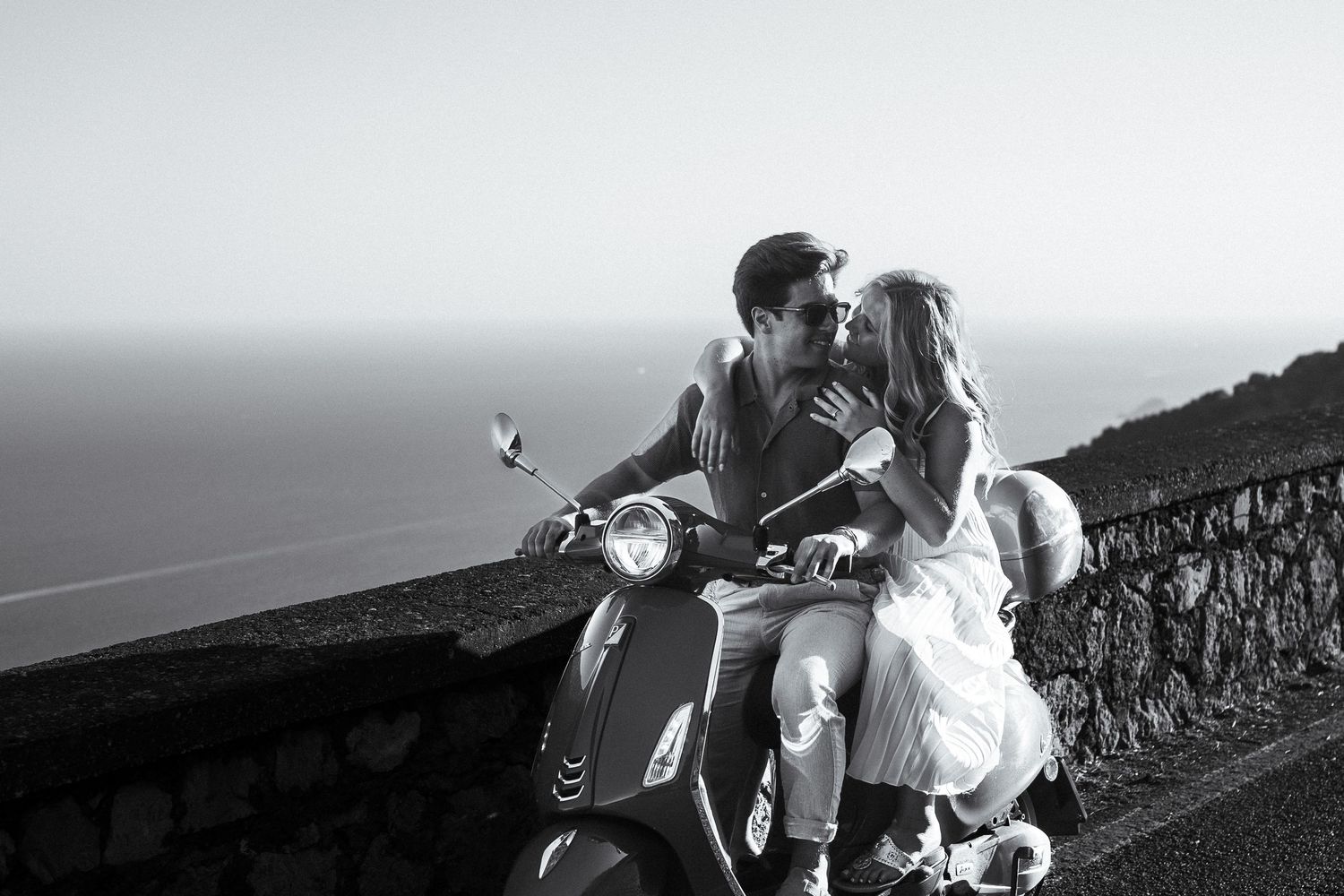Newly engaged couple sitting on a Vespa during sunset along the Amalfi Coast in Italy