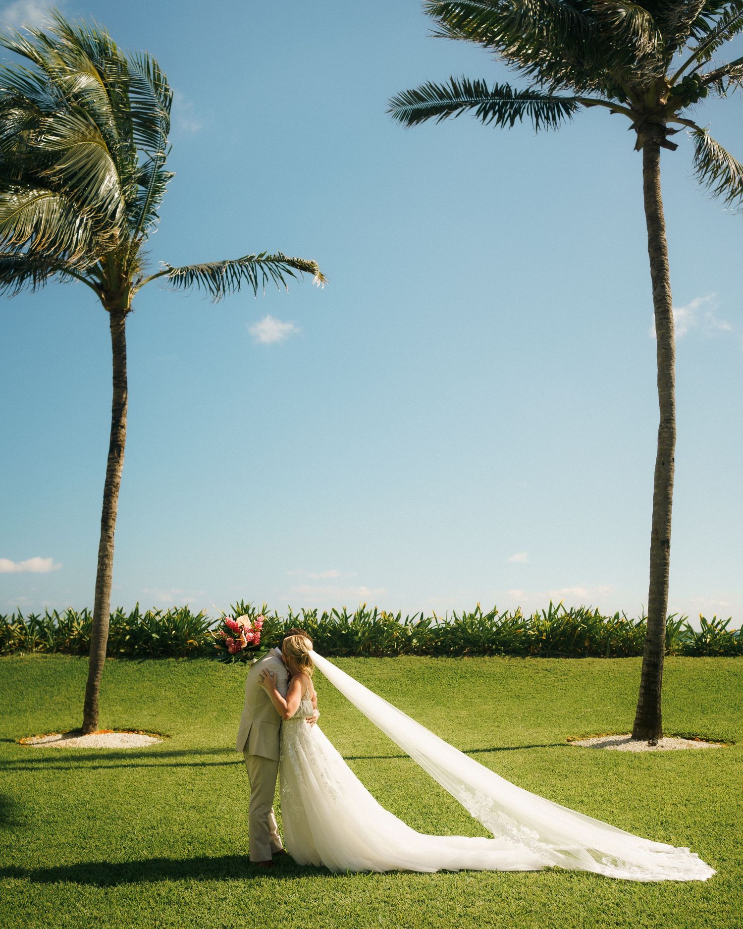 Bride and Groom embrace during their first look in front of palm trees at Dreams Jade Resort in Cancún, Mexico.