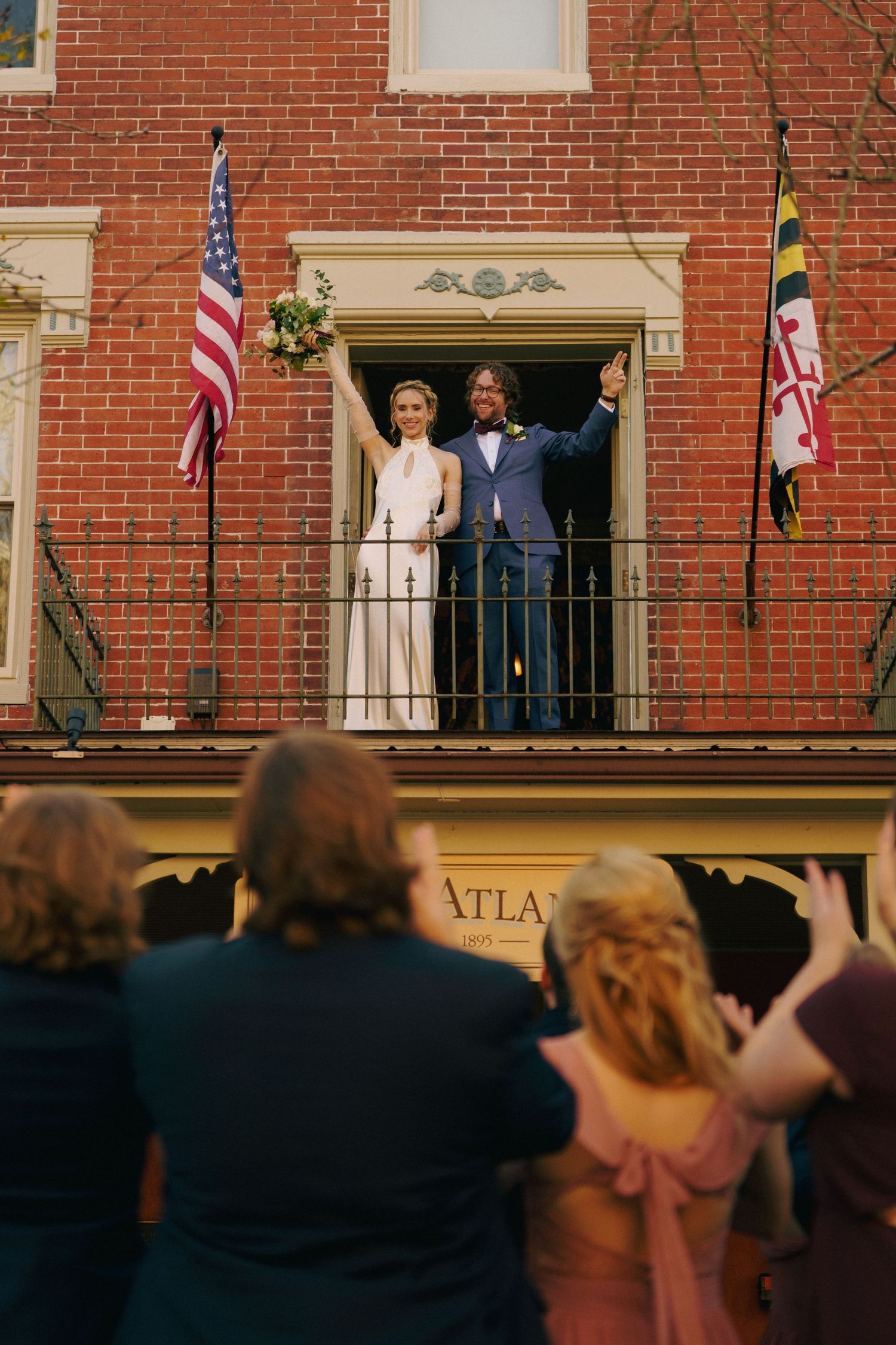 Bride and Groom wave to the wedding party while standing on the balcony of the Atlantic Hotel in Berlin, Maryland.