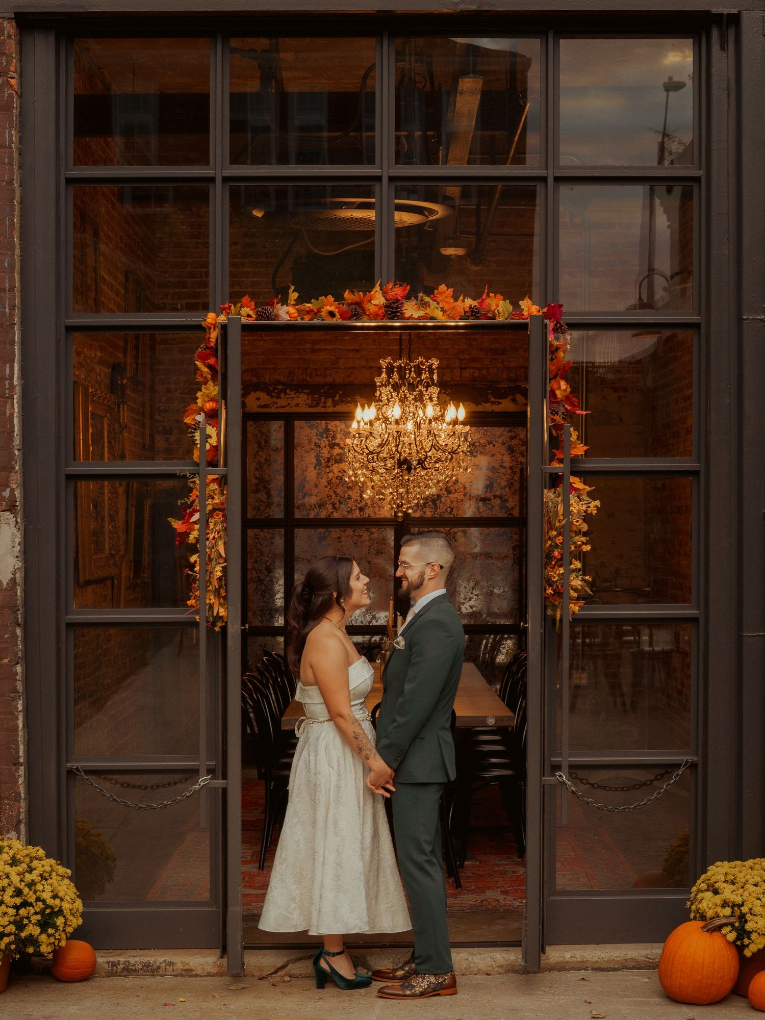 Bride and Groom hold hands in front of autumn decorations at Guilford Hall Brewery in Baltimore, Maryland.