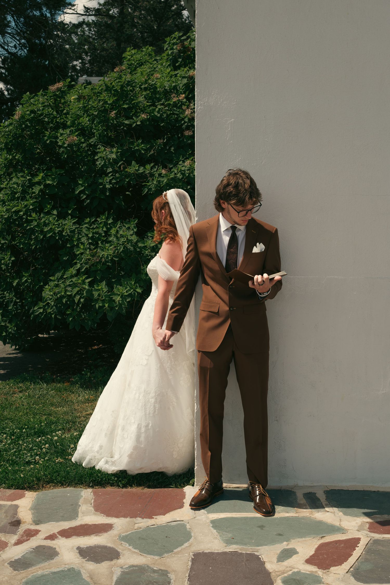Bride and groom standing back-to-back outside before wedding ceremony.