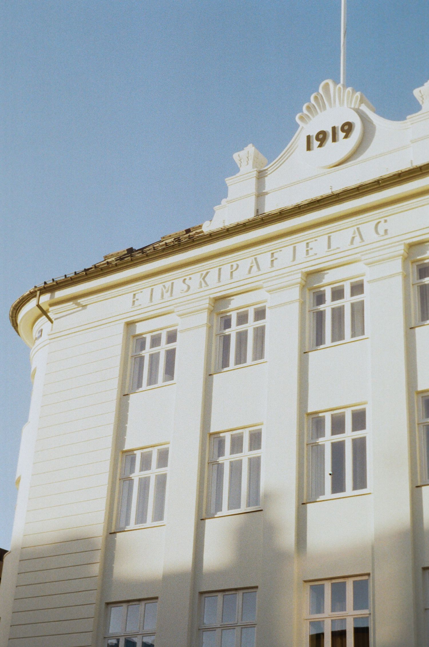 White art deco style building facade with 1919 inscription and ornate architectural details in sunlight.