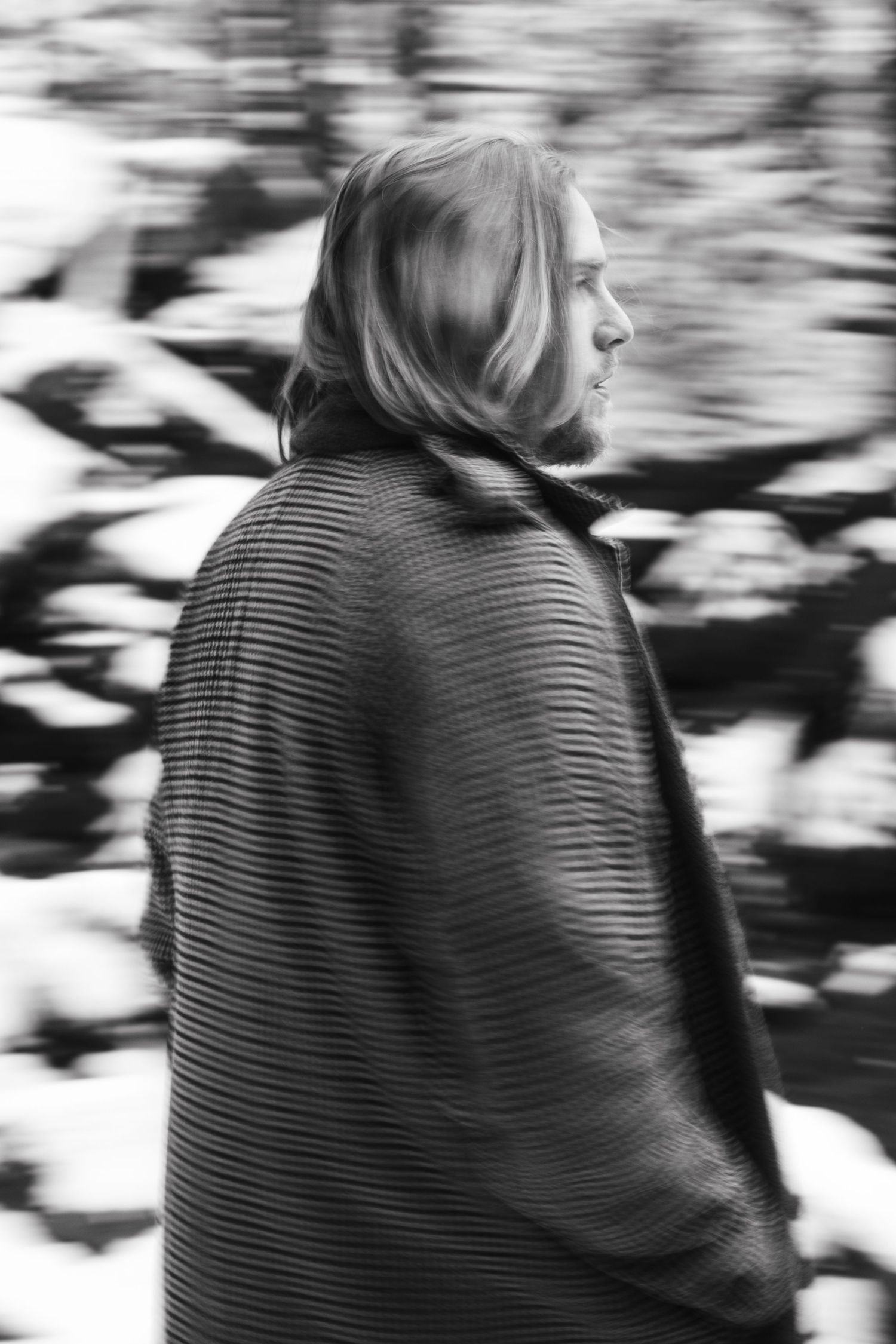 A black and white motion blur photograph shows someone in a striped jacket facing away from the camera.