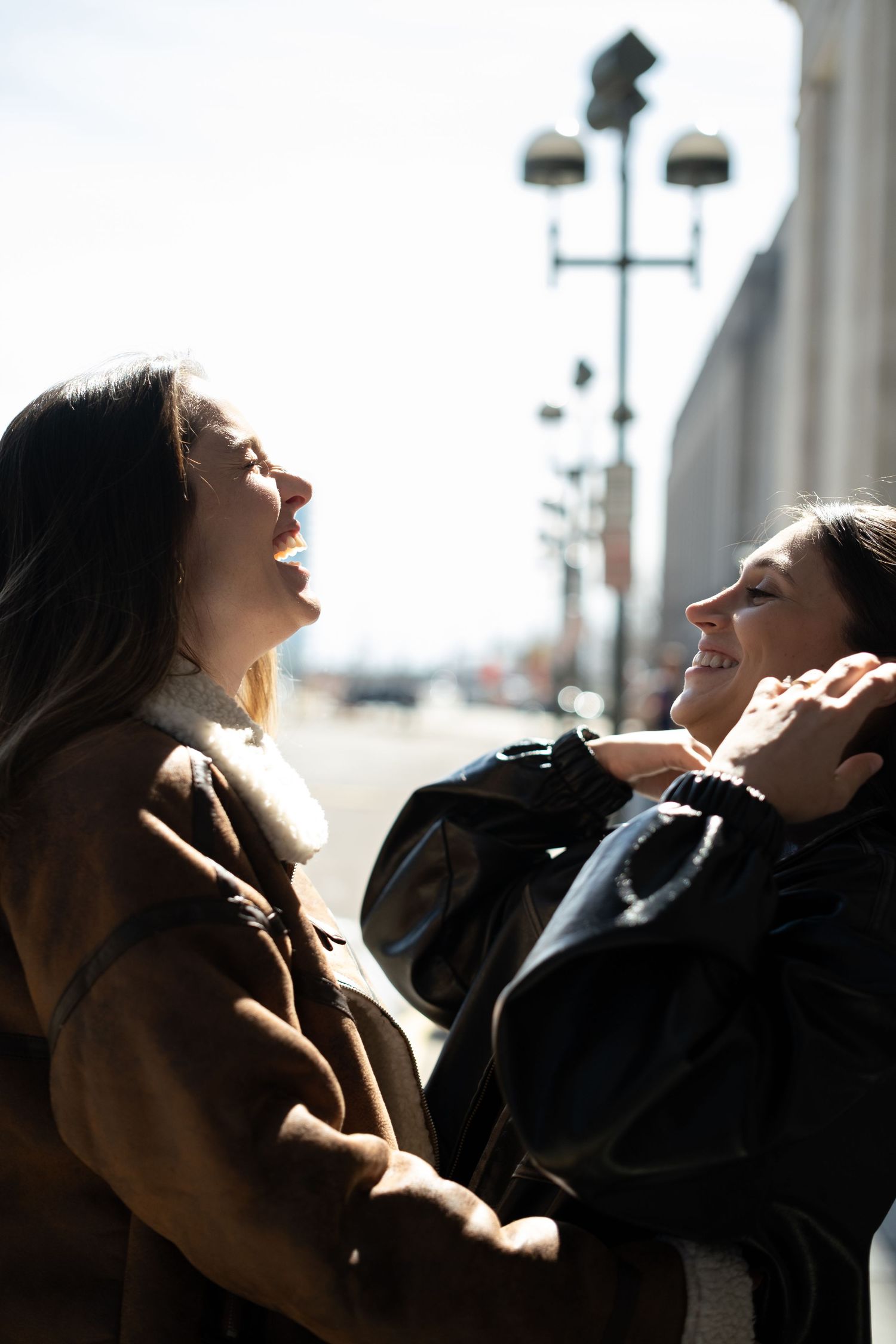 A couple embraces in dramatic side lighting creating silhouettes against a bright background.