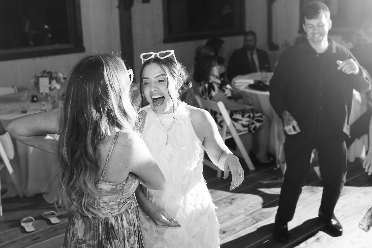 Joyful wedding guests laughing and dancing together at fun indoor wedding reception party.