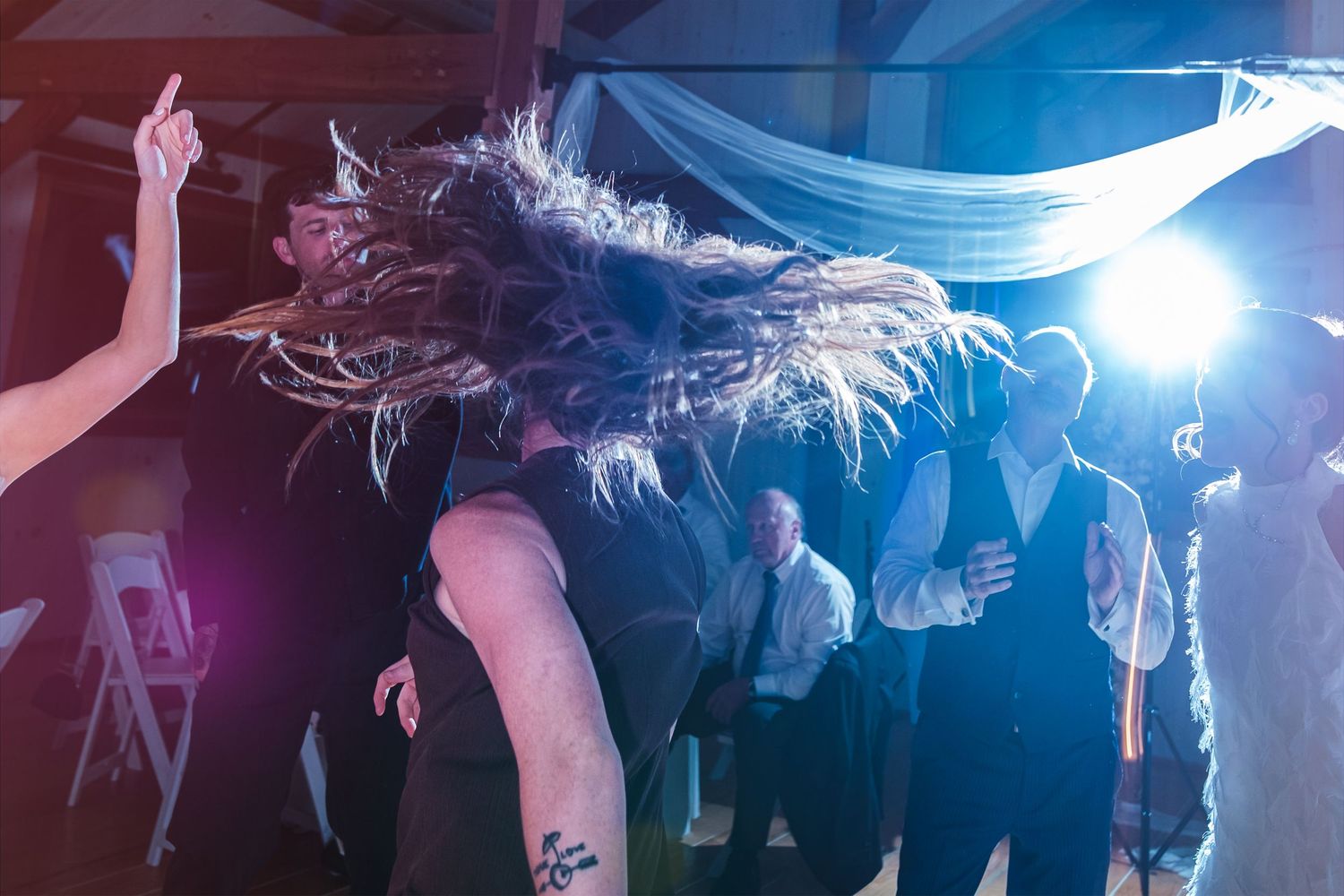Guest energetically headbanging on the wedding dance floor during lively wedding reception celebration.