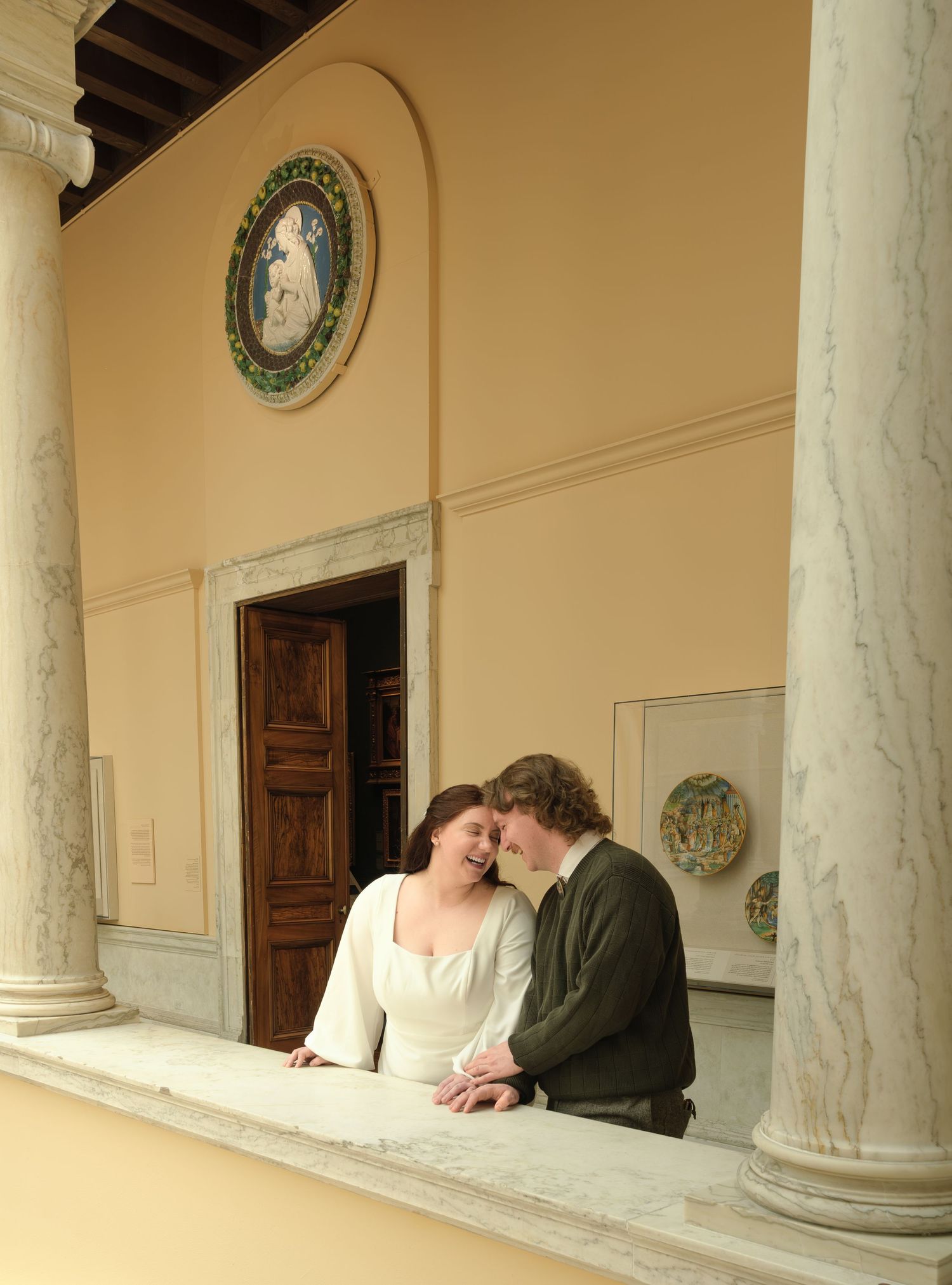 Couple sharing a romantic moment on a balcony with marble columns in an elegant Italian villa.
