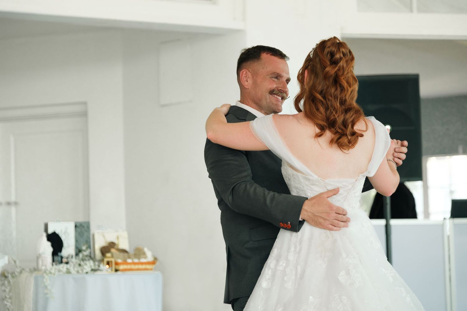 Father daughter first dance at wedding reception in bright white venue.