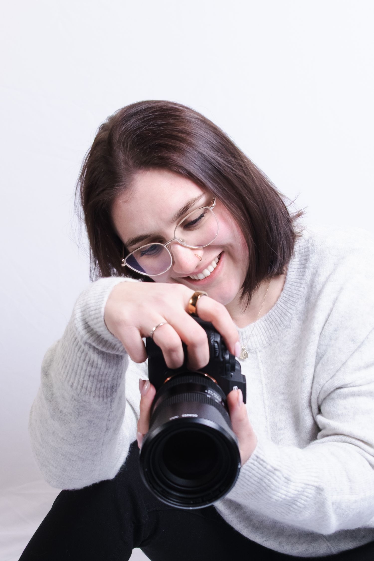 A series of four photos showing someone in a white sweater holding and looking through a camera lens.
