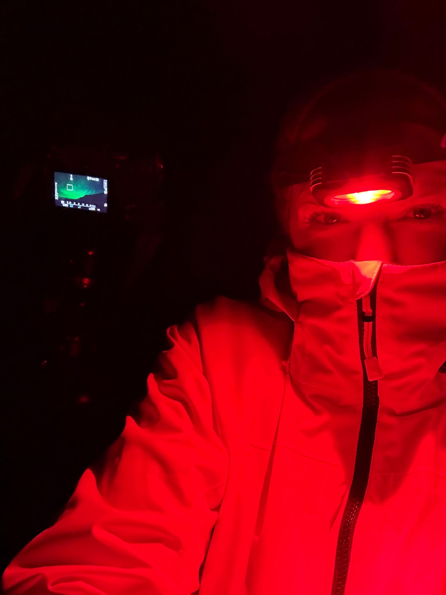 Dark interior of a vehicle illuminated by red ambient lighting creating a moody atmospheric glow.