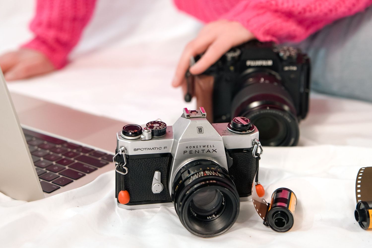 A collection of vintage and modern cameras and photography equipment arranged in a row on a white surface.
