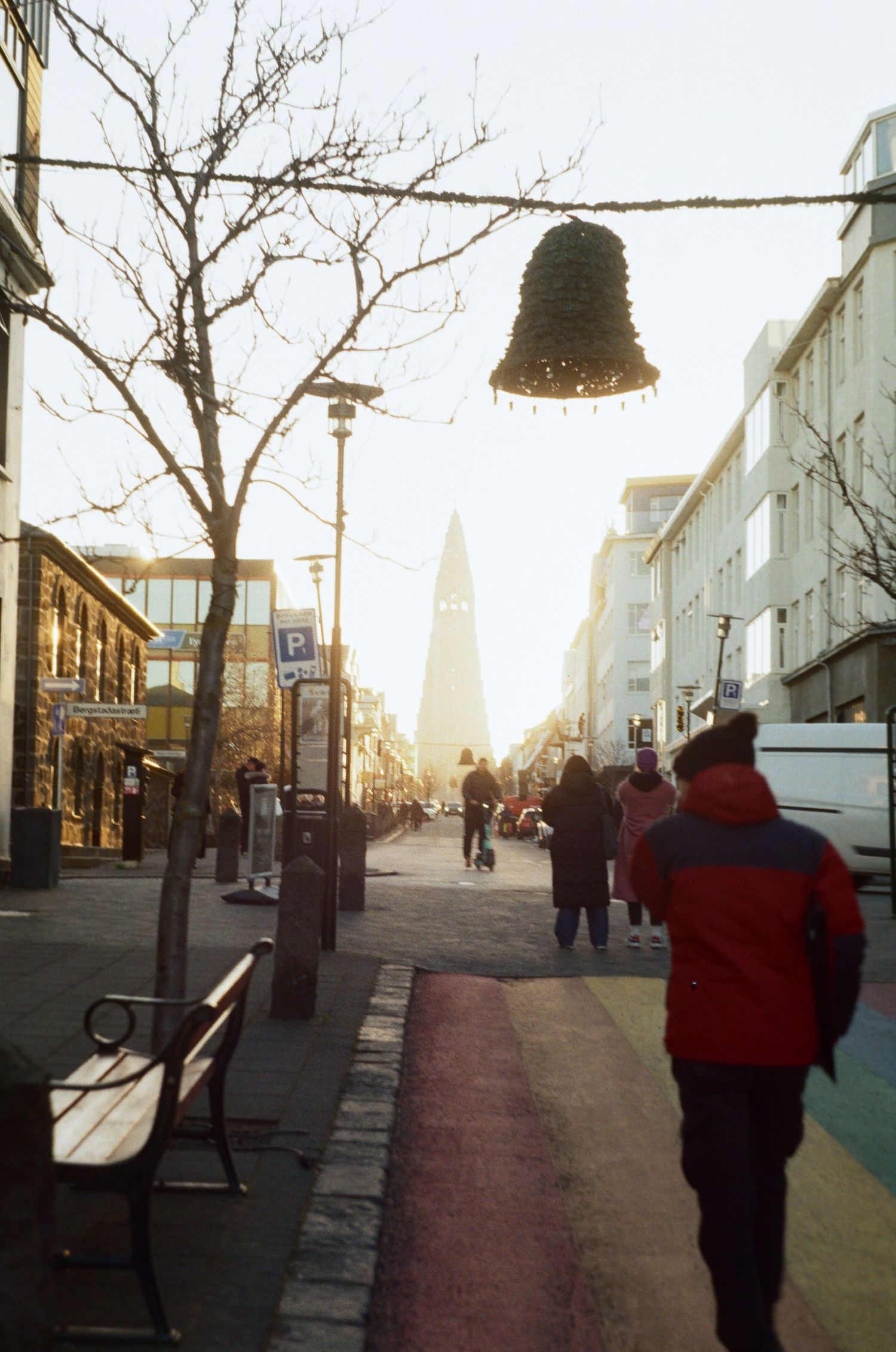 A series of five connected photos showing a person walking down a sunlit urban street with buildings and bare trees.