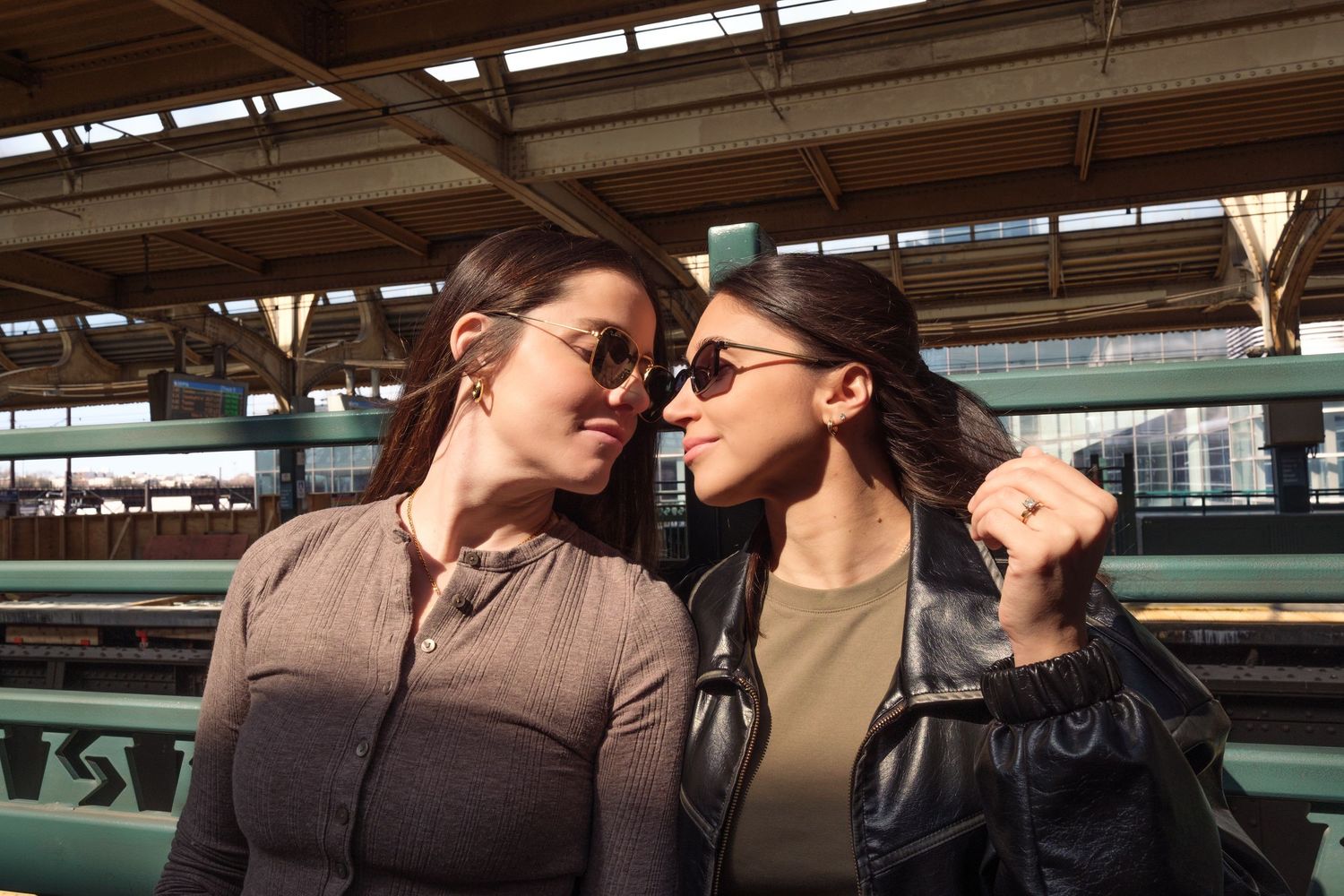 Two people share an intimate moment while sitting on a train platform bench.