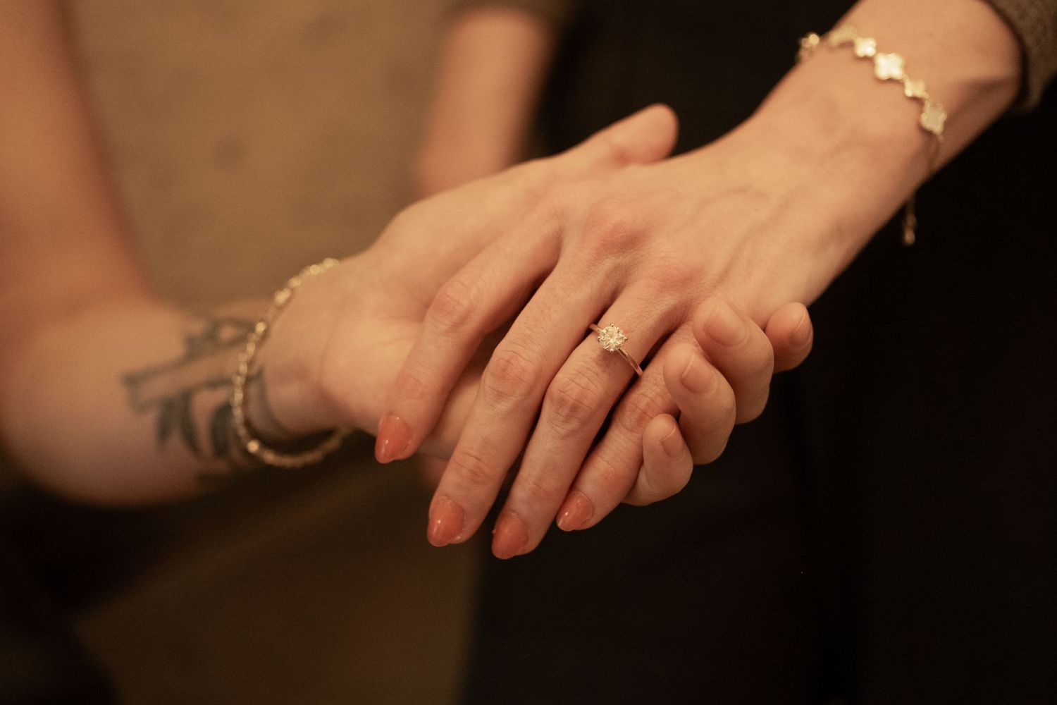 Hands with tattoos holding a small white and black spotted dog while trimming its nails.