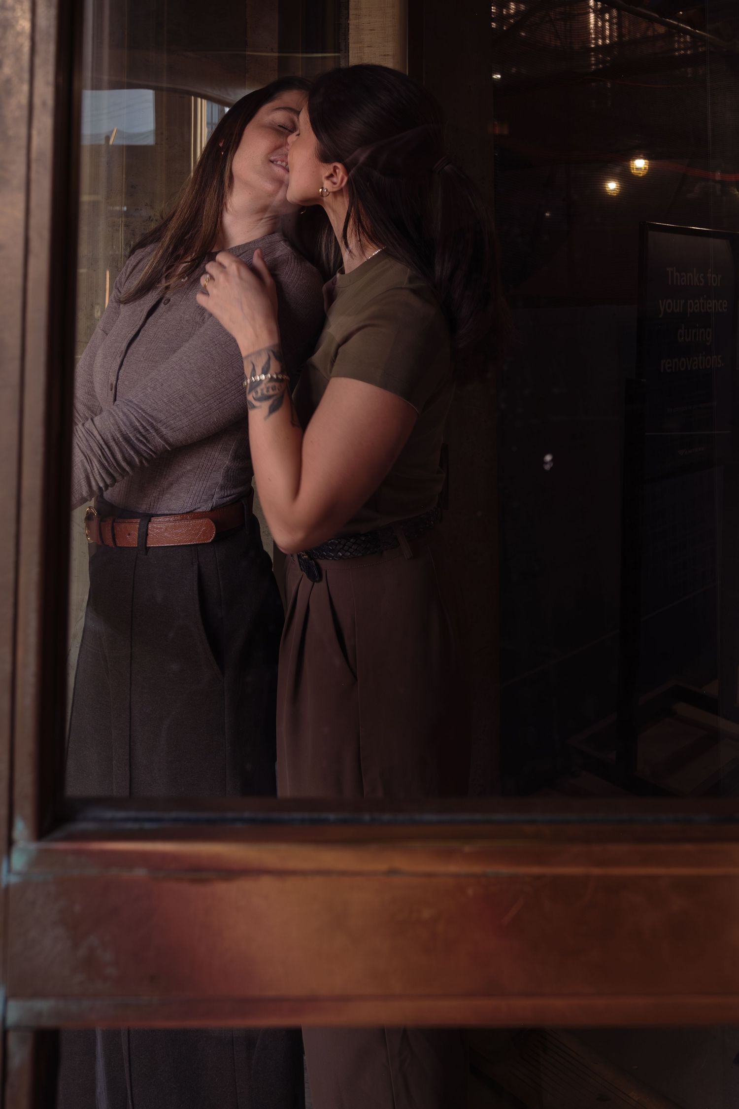 A romantic couple embraces and kisses in a dimly lit room with reflective surfaces creating multiple silhouettes.