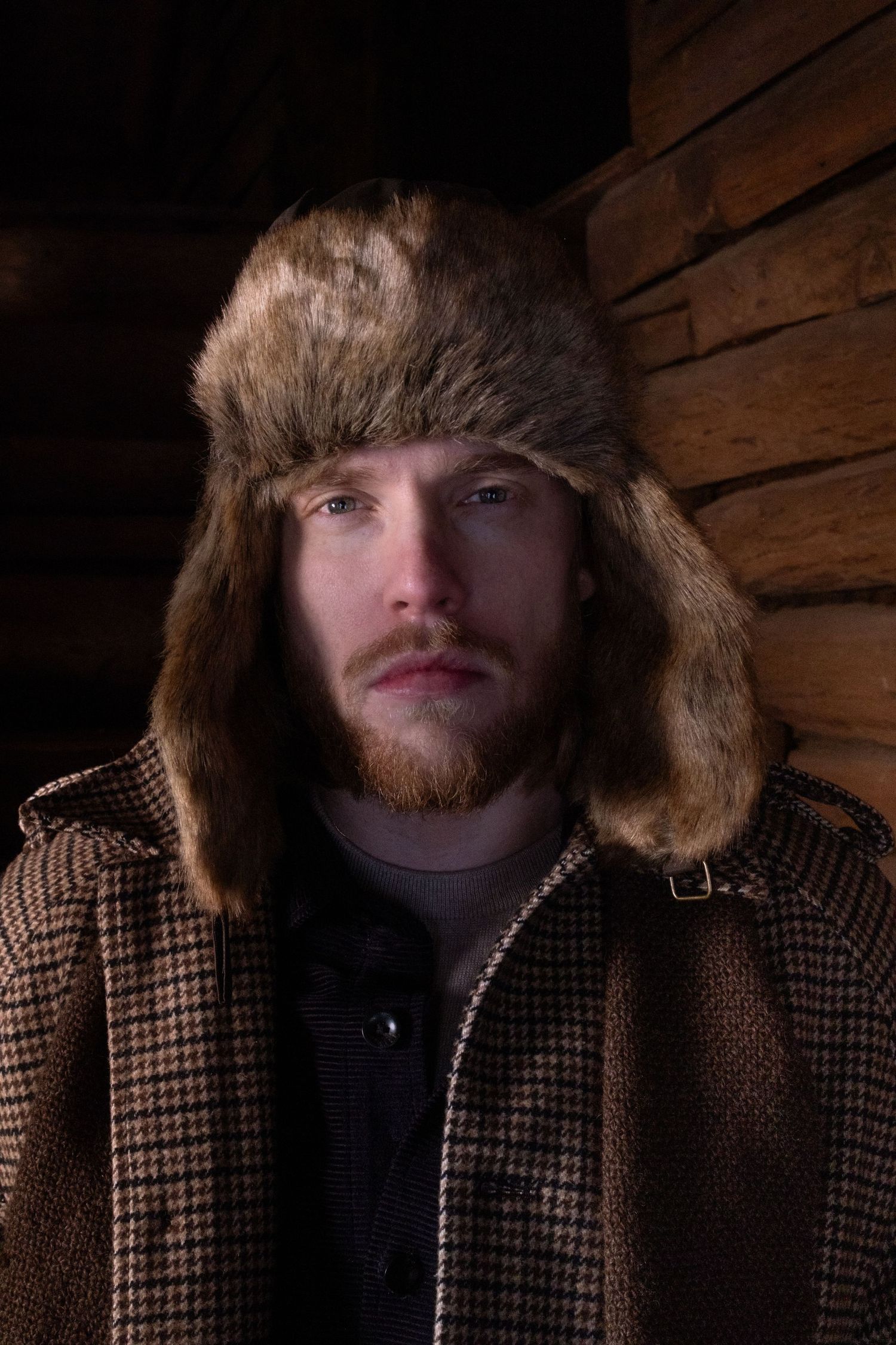 A series of eight close-up photos showing someone wearing a plaid winter coat with fur trim and a beard in dark lighting.
