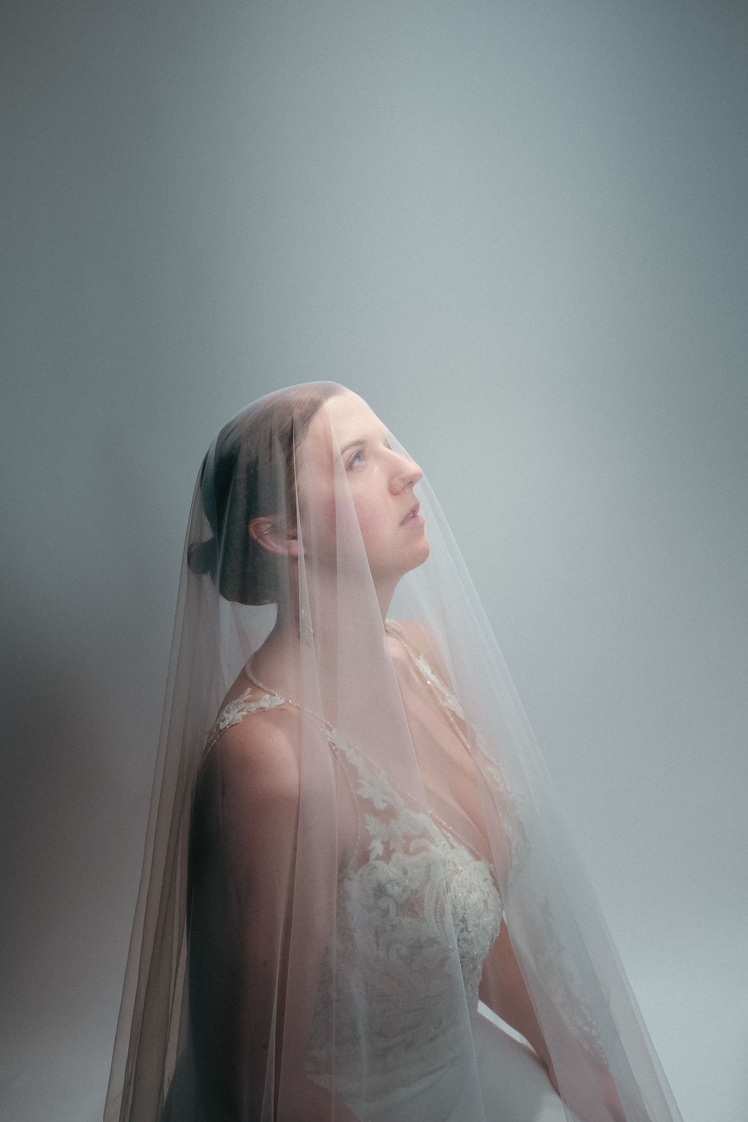 A series of ethereal bridal portraits showing a veiled figure in soft, misty lighting against a gray background.