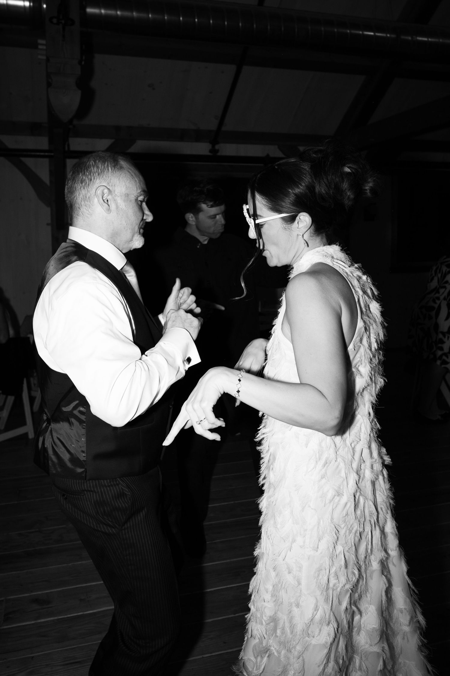 Black and white photo of a couple dancing together at a wedding reception, woman in feathered dress.