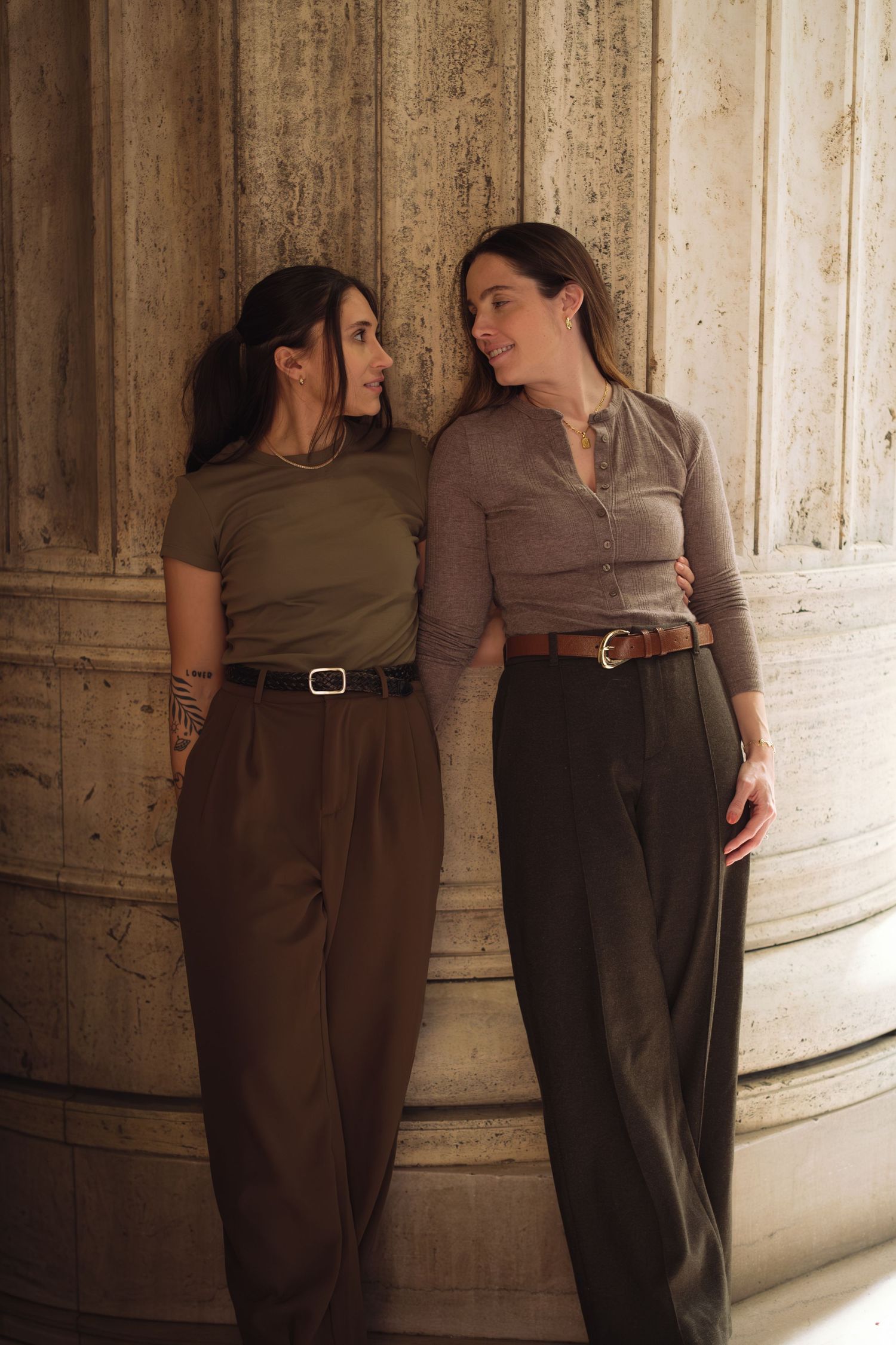 Two people lean against a textured wall in a series of intimate poses wearing earth-toned clothing.