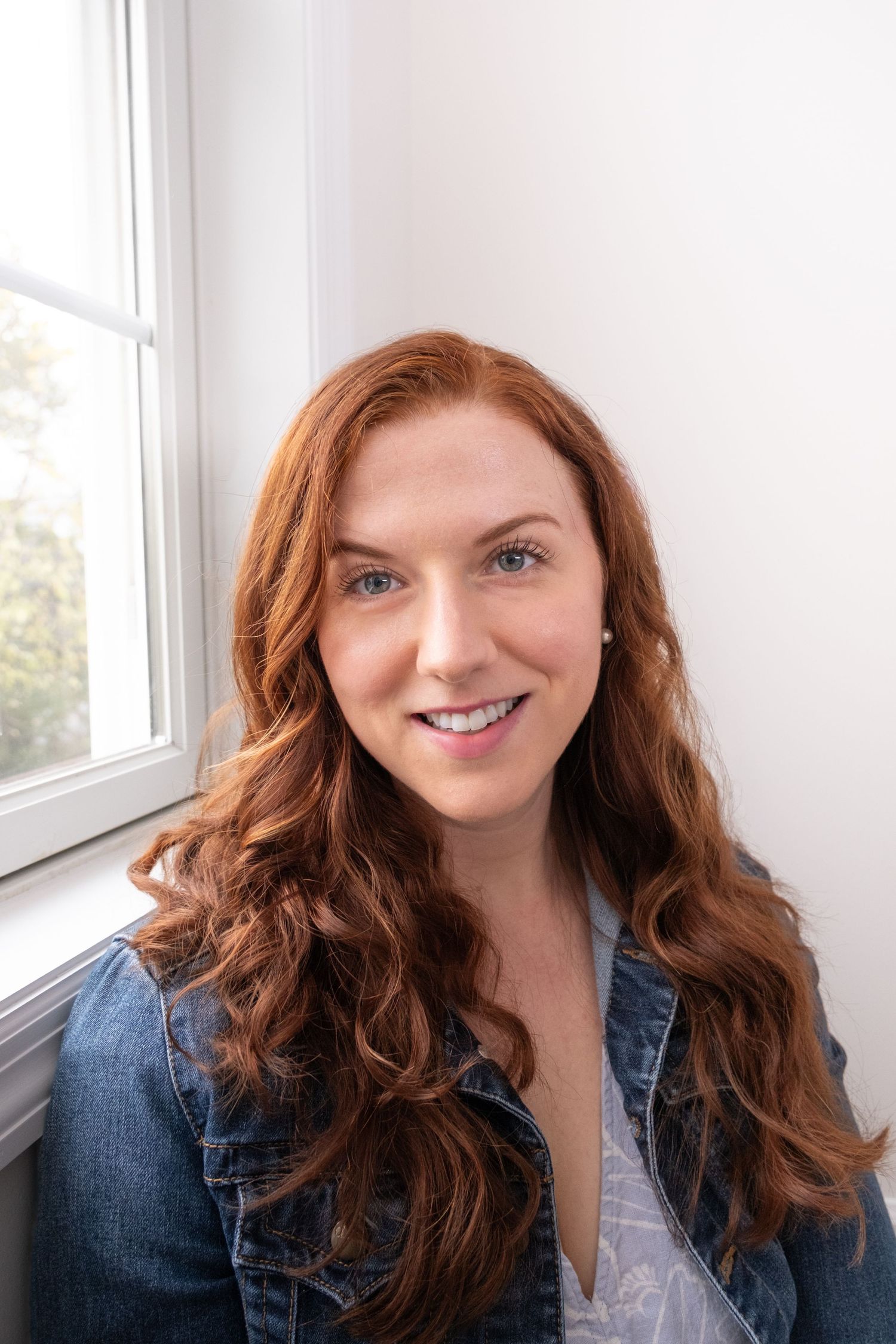 A woman with long red wavy hair smiles warmly while wearing a denim jacket in a series of four similar photos.
