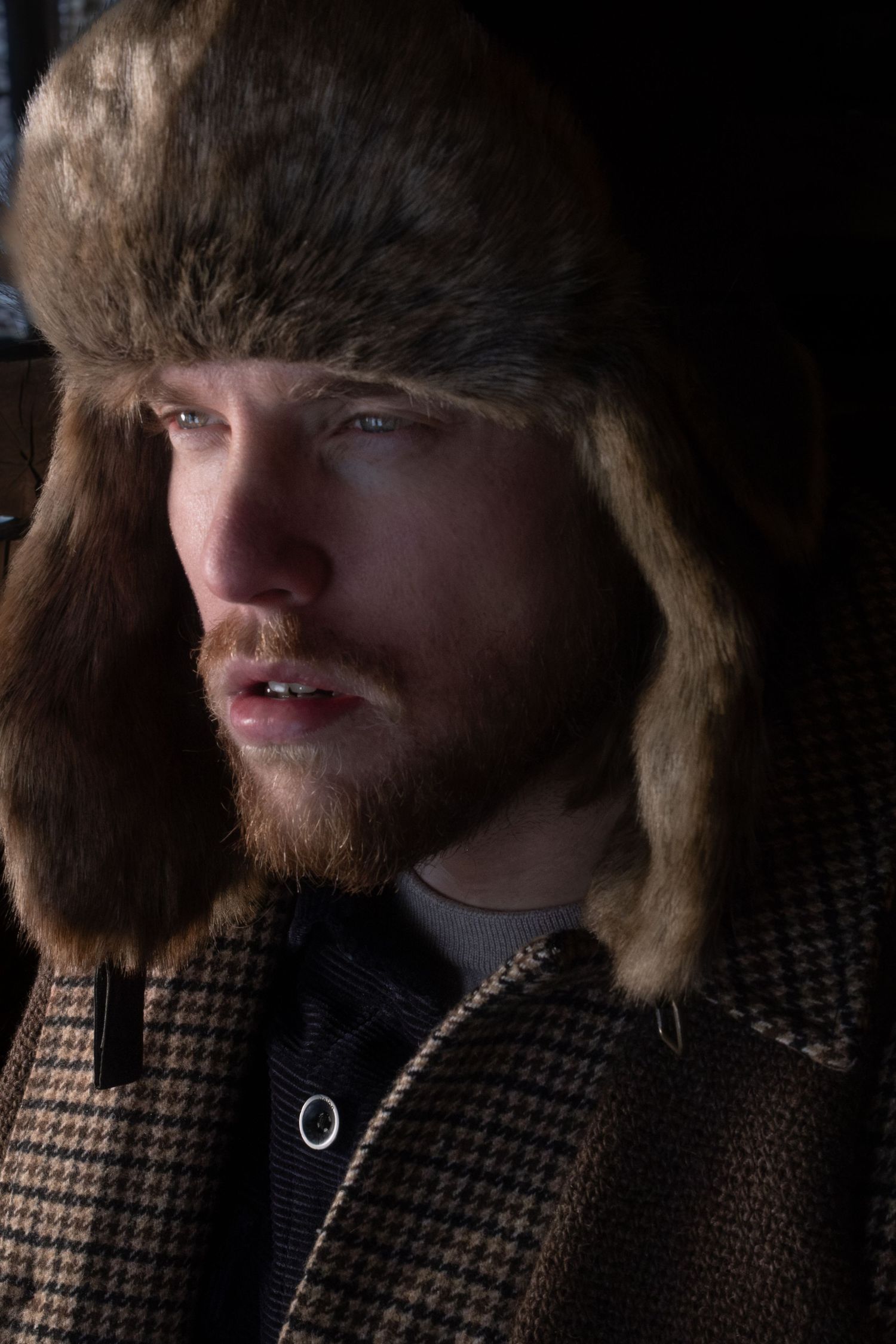 A series of moody portraits showing a person with a red beard wearing a plaid jacket against a dark background.
