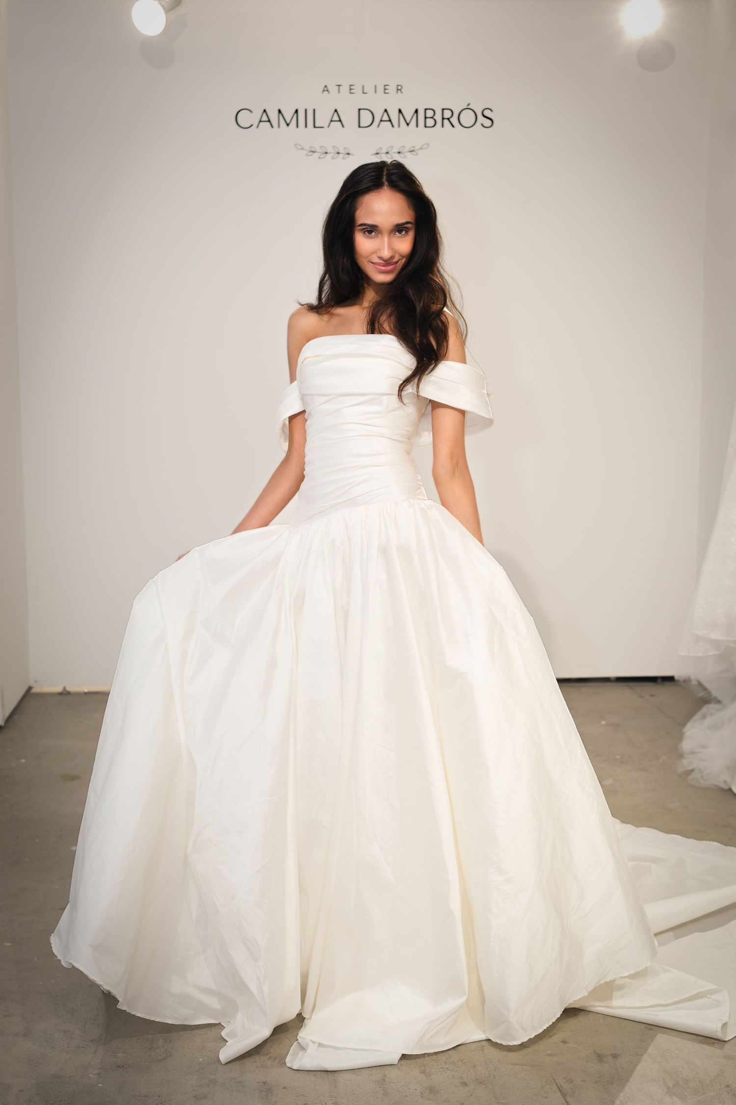 Bride in an ivory off-the-shoulder Atelier Camila Dambrós ball gown with a ruched bodice, full taffeta skirt and long train.