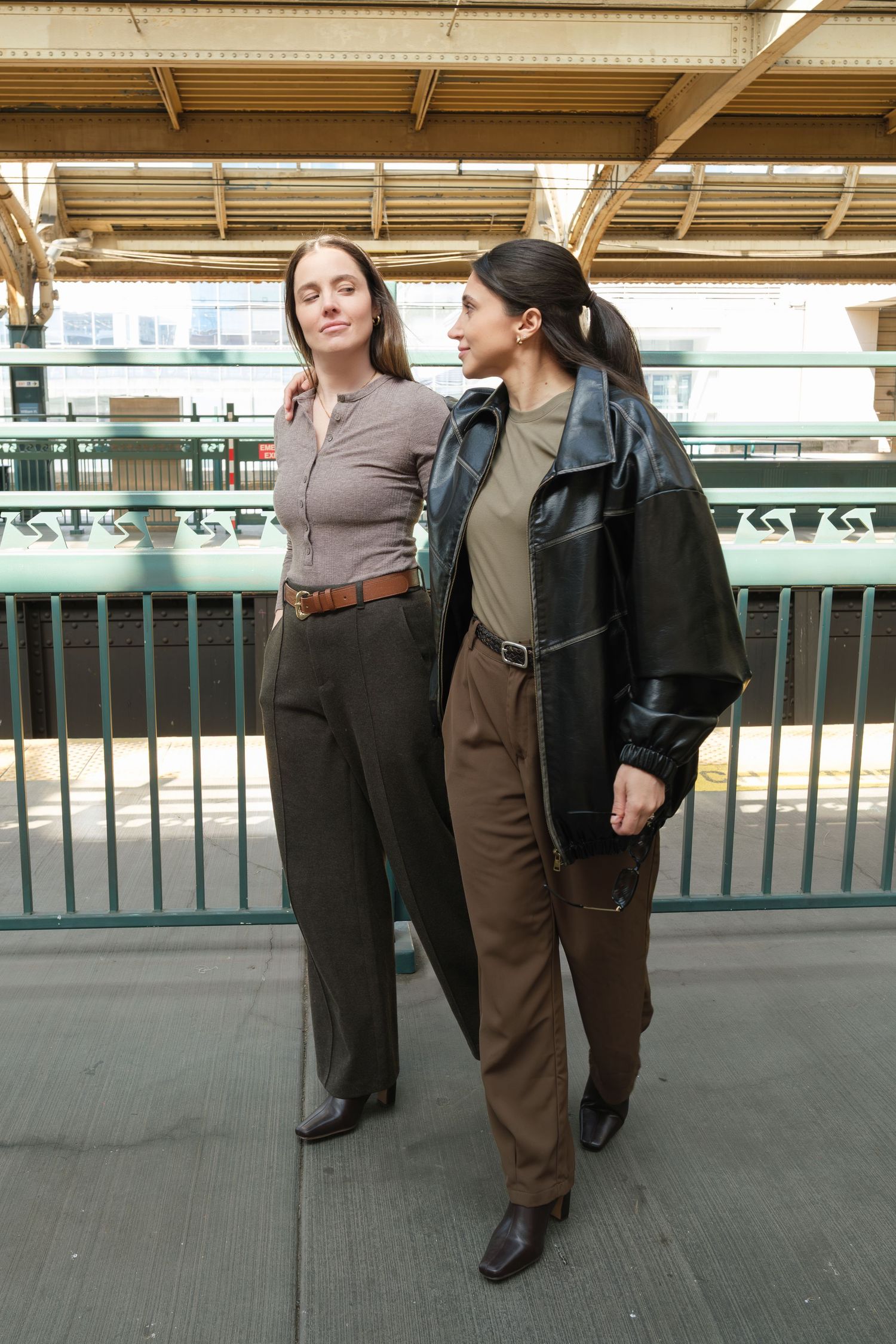 Two people in business attire walk together along a train station platform.