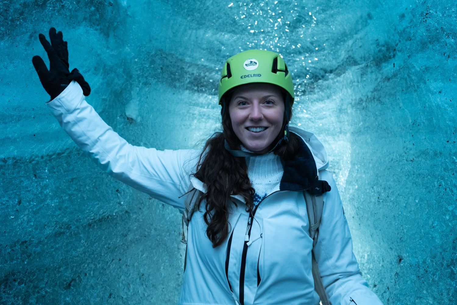Climbers explore a stunning ice cave with bright blue glacial walls and illuminated passages in Iceland.