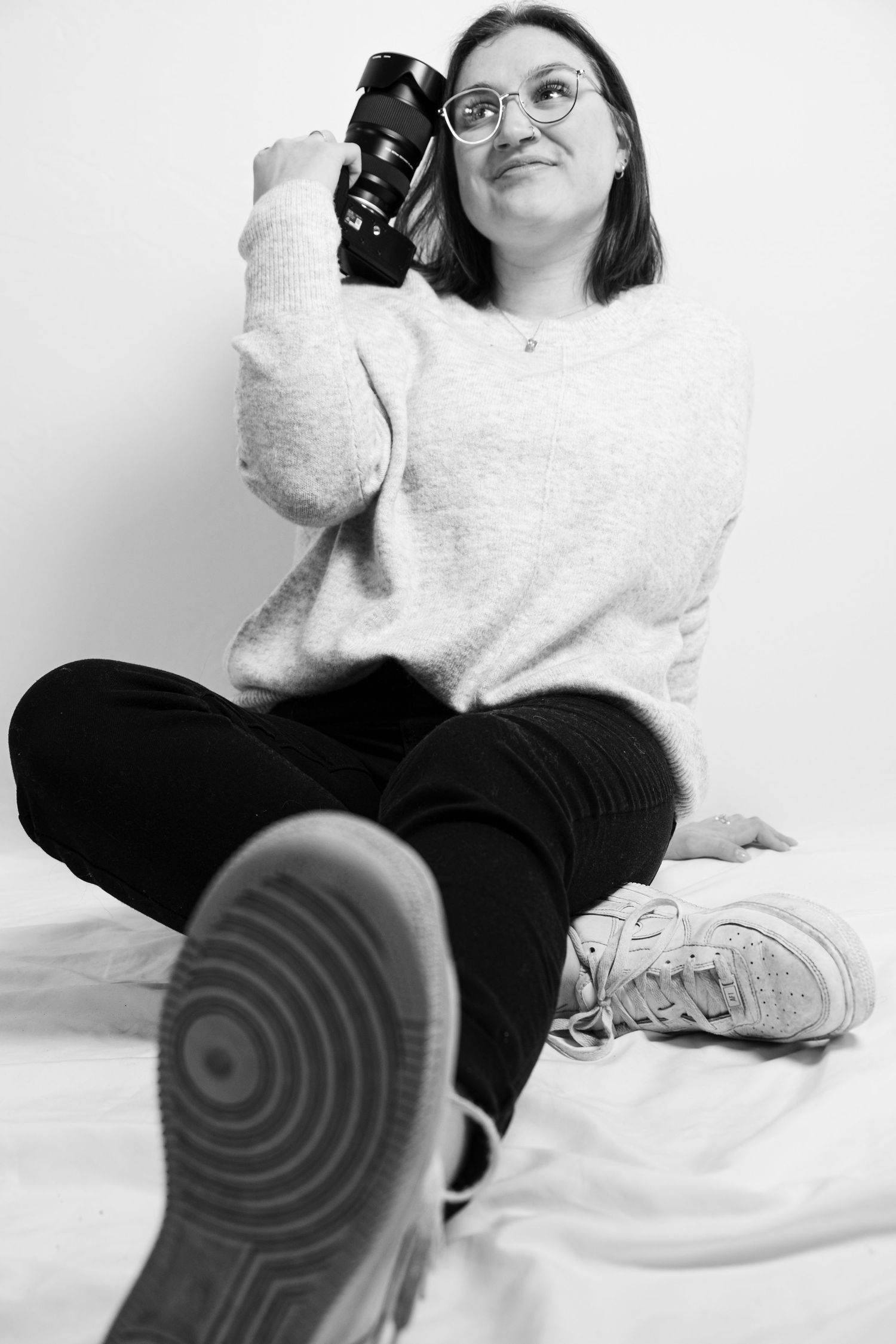 Black and white series showing someone relaxing in casual clothes against white background in various lounging poses.