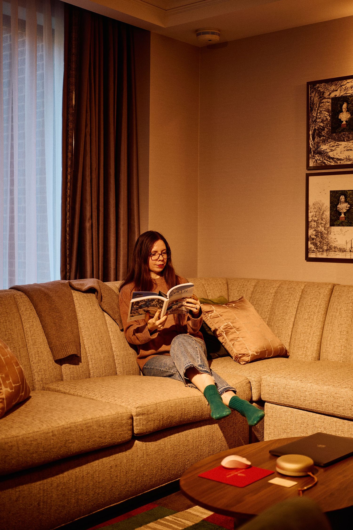 Person relaxing on beige sectional sofa in warmly lit living room.