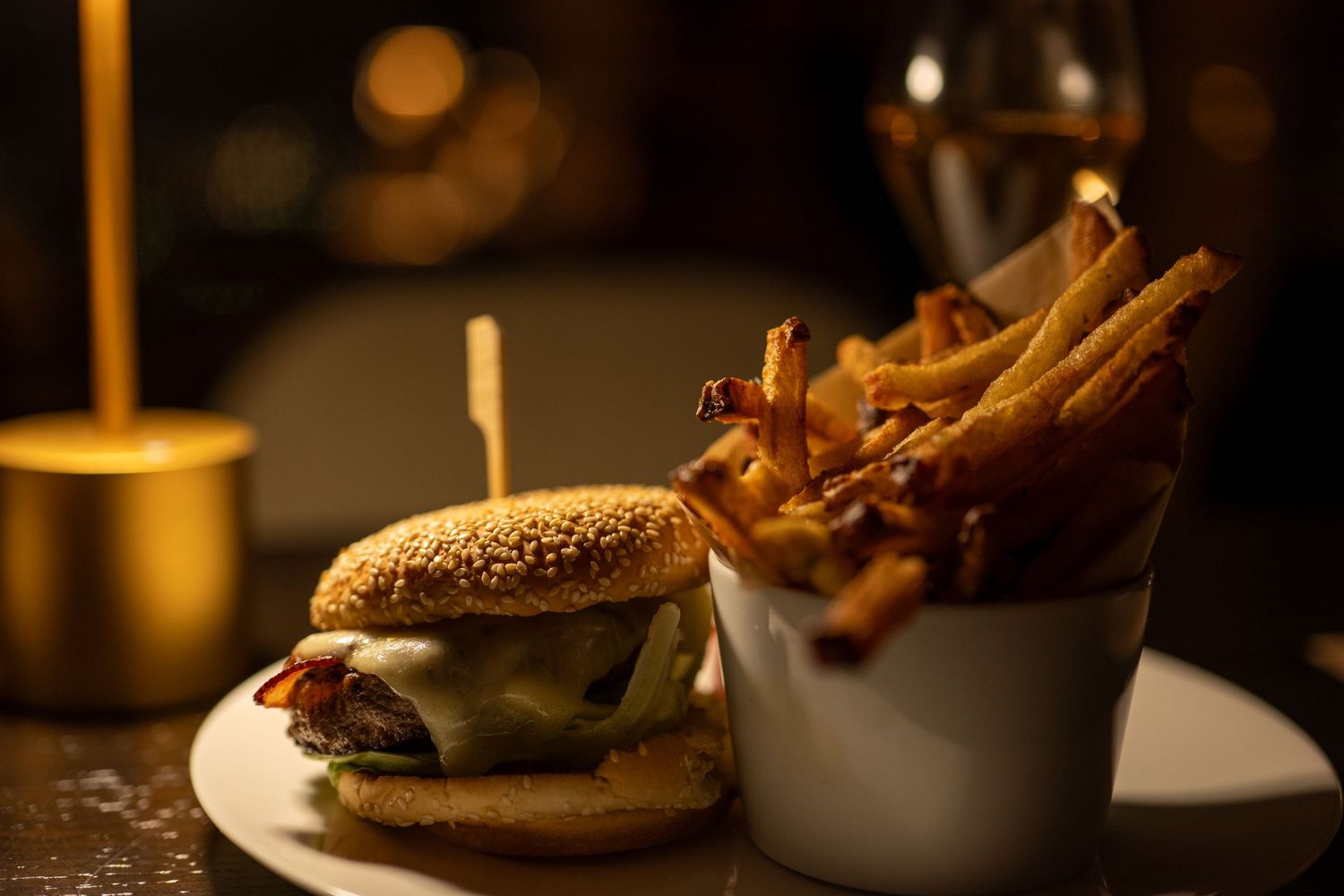Artisanal burger with melted cheese and bacon served on a rustic wooden board in warm lighting.