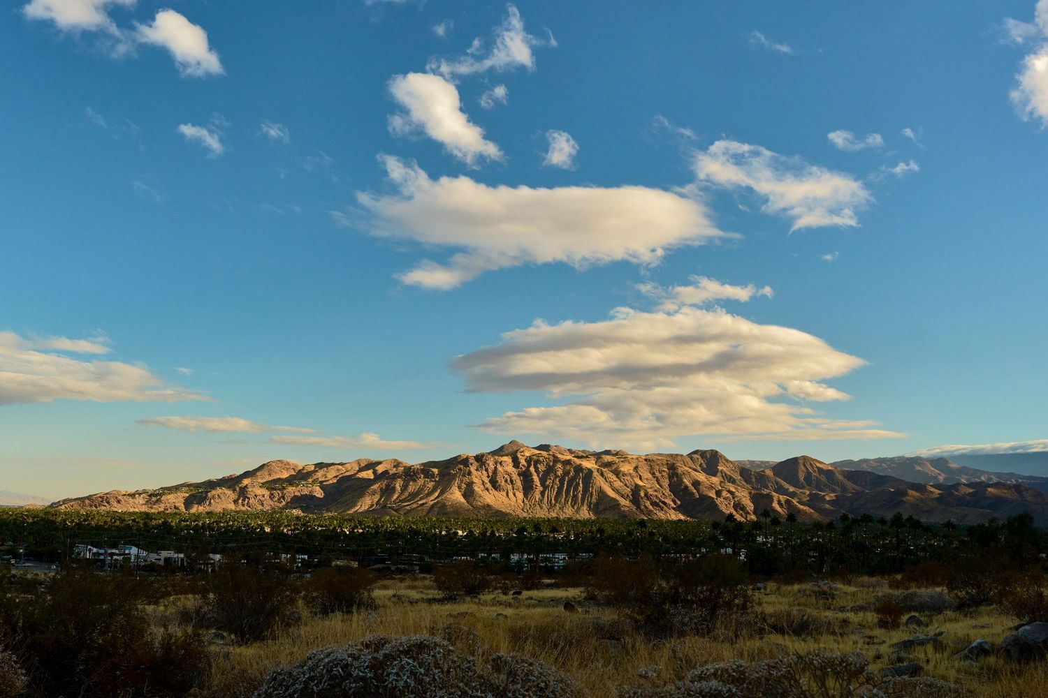 Panoramic mountain landscape with blue skies and white clouds stretching across the horizon.