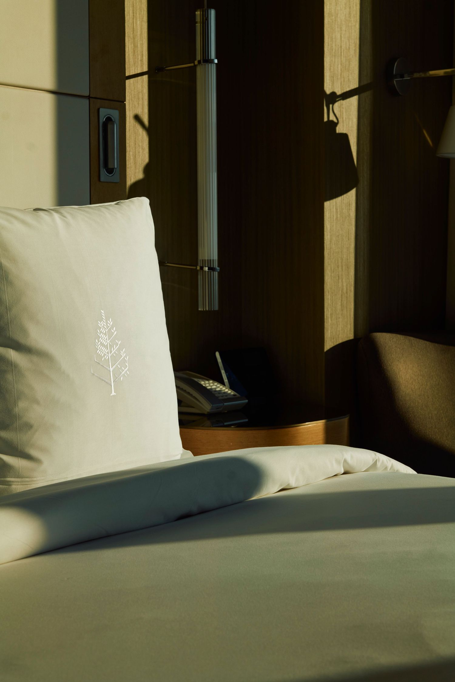White hotel pillows and bedding illuminated by natural sunlight through window.