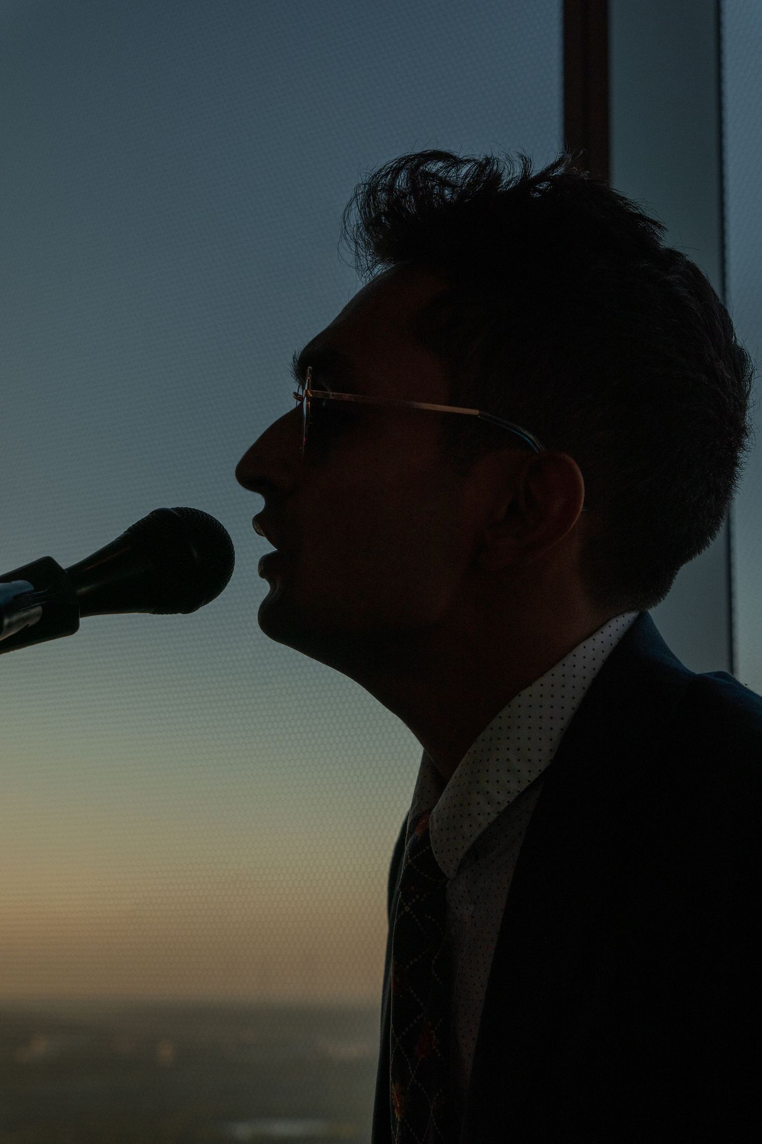 Silhouette of person drinking against sunset window view.