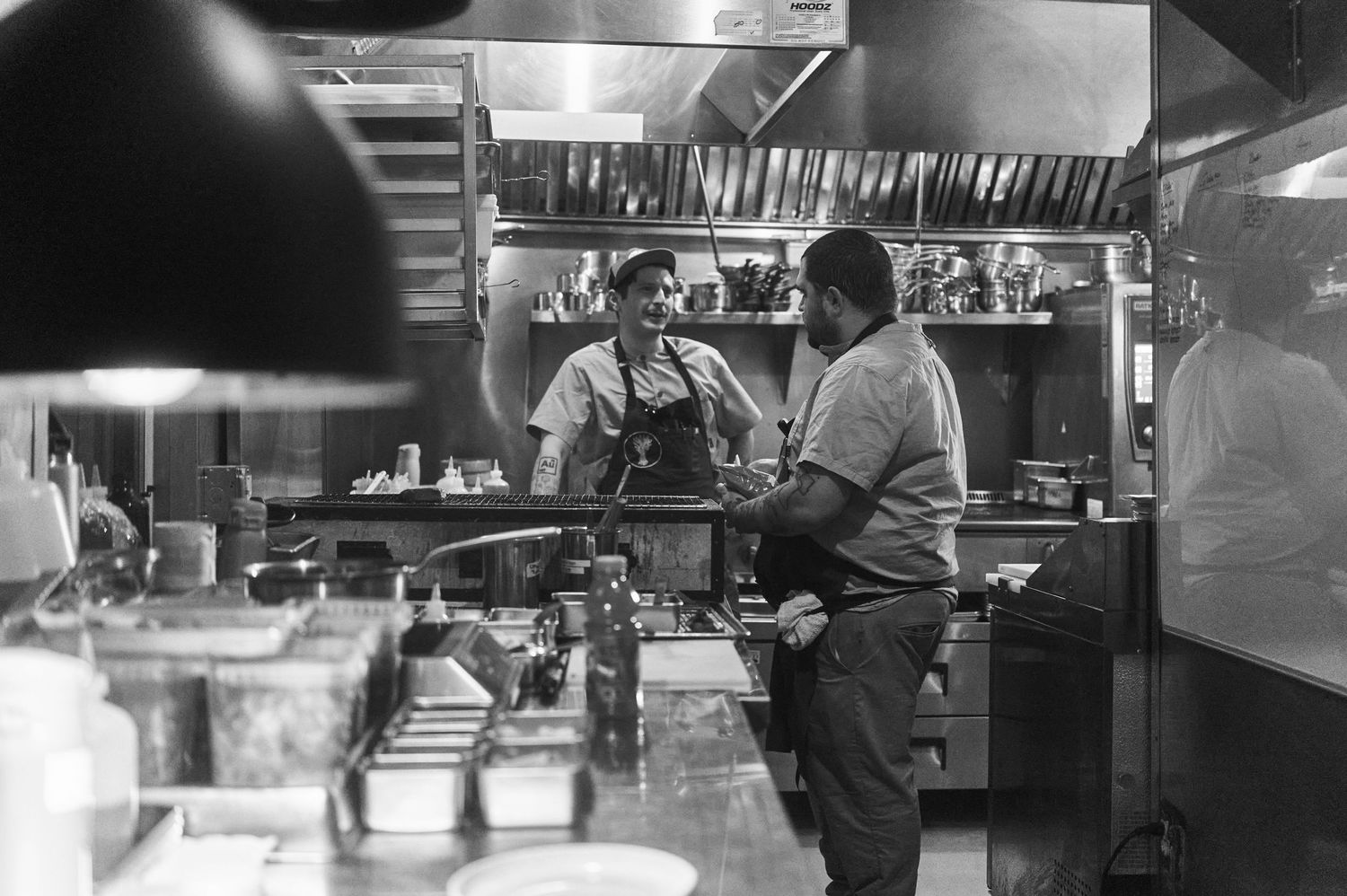 Commercial kitchen interior with stainless steel equipment and staff at work.