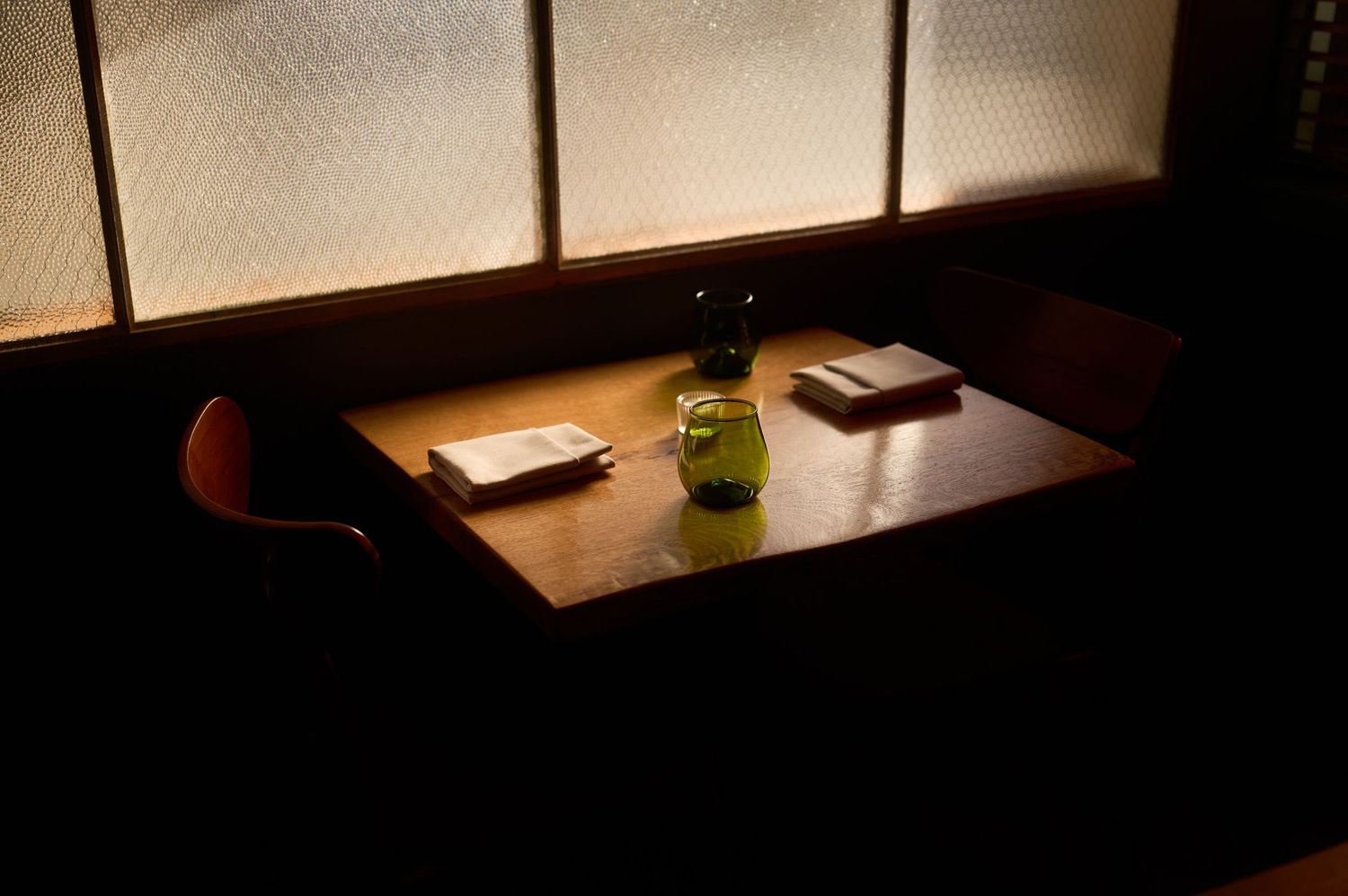 Dimly lit restaurant interior with ambient window lighting.