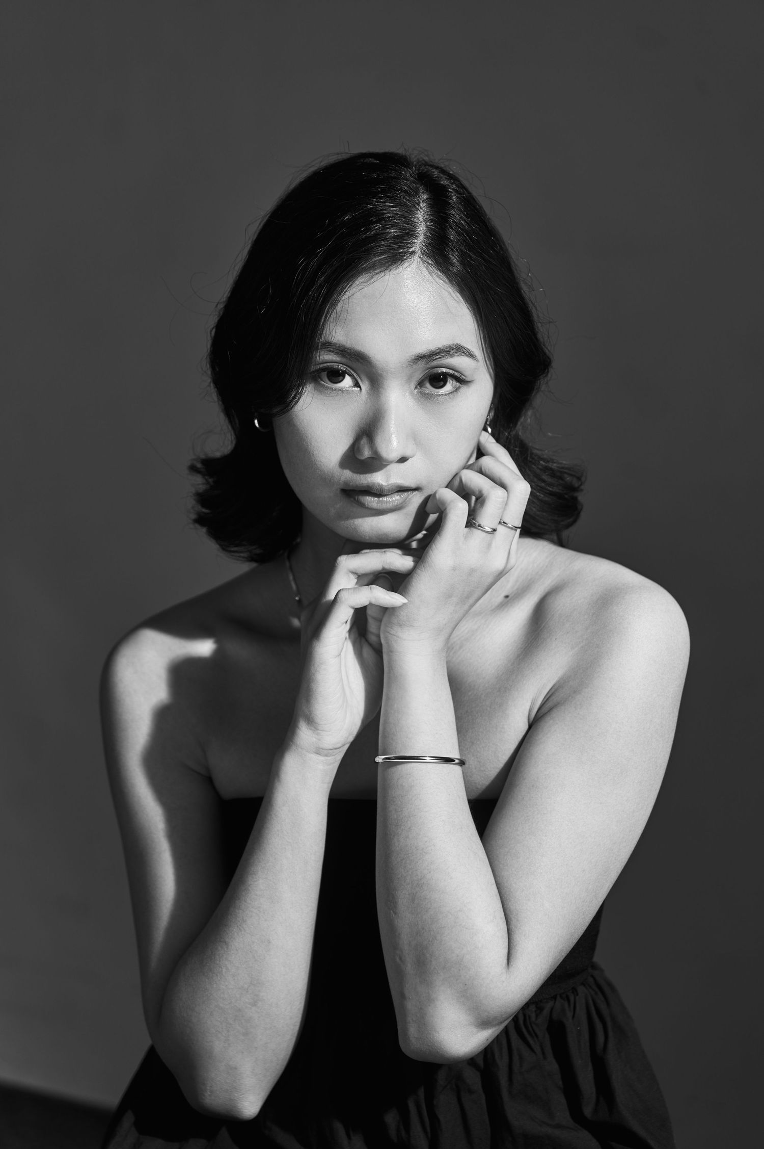 Black and white artistic portrait series showing expressive poses with hands near face against dark background.