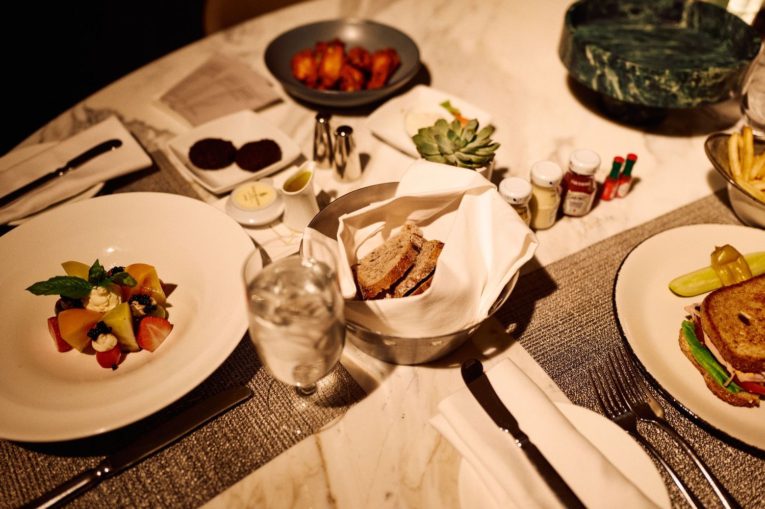 Elegant dinner table setting with multiple courses and ambient lighting.