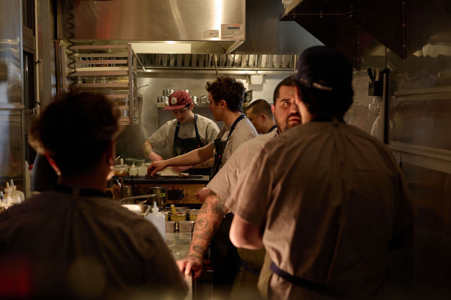 Restaurant kitchen staff working at counter during dinner service in low lighting.