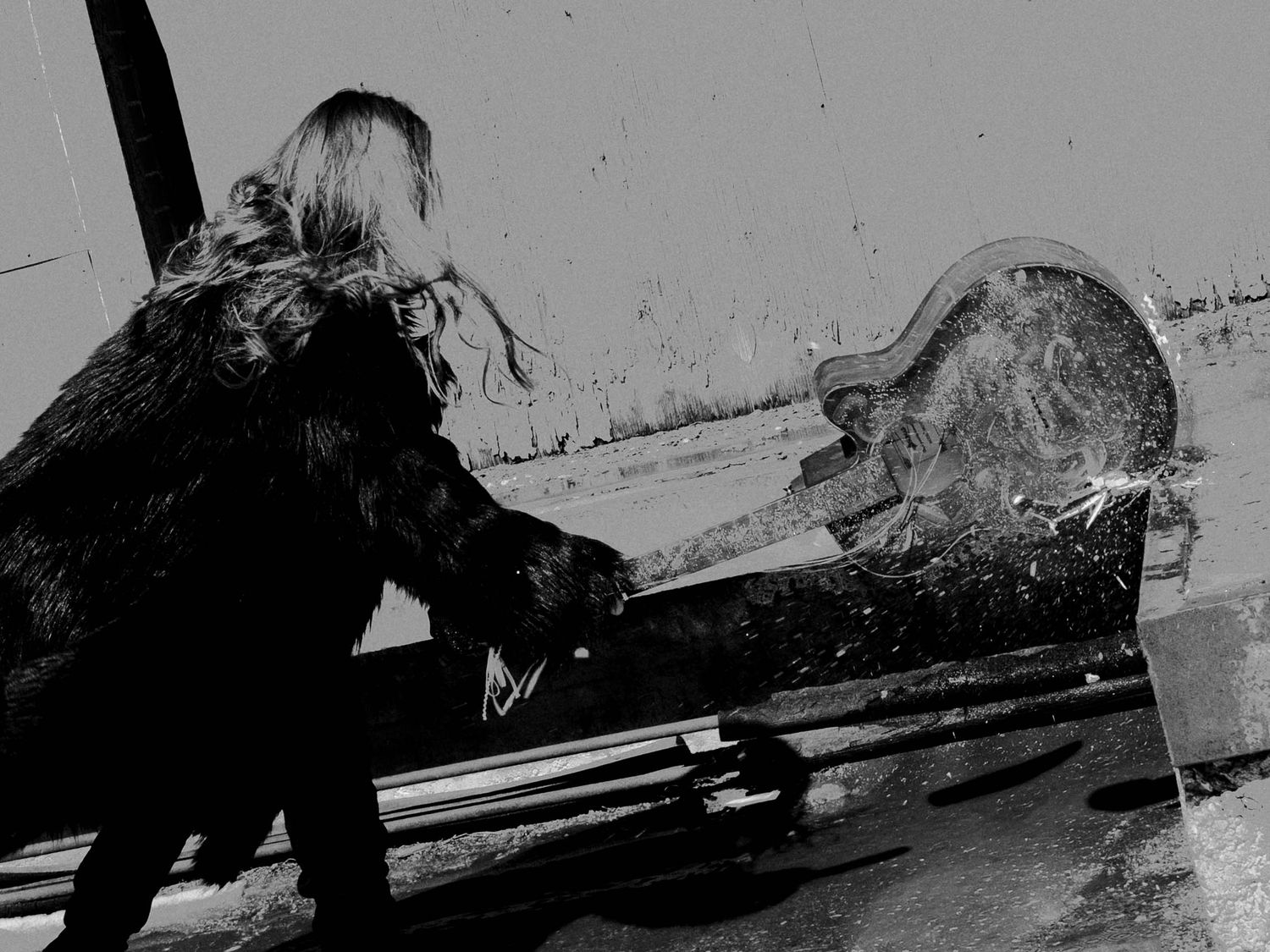 Black and white creative portrait of woman smashing an acoustic guitar on cement