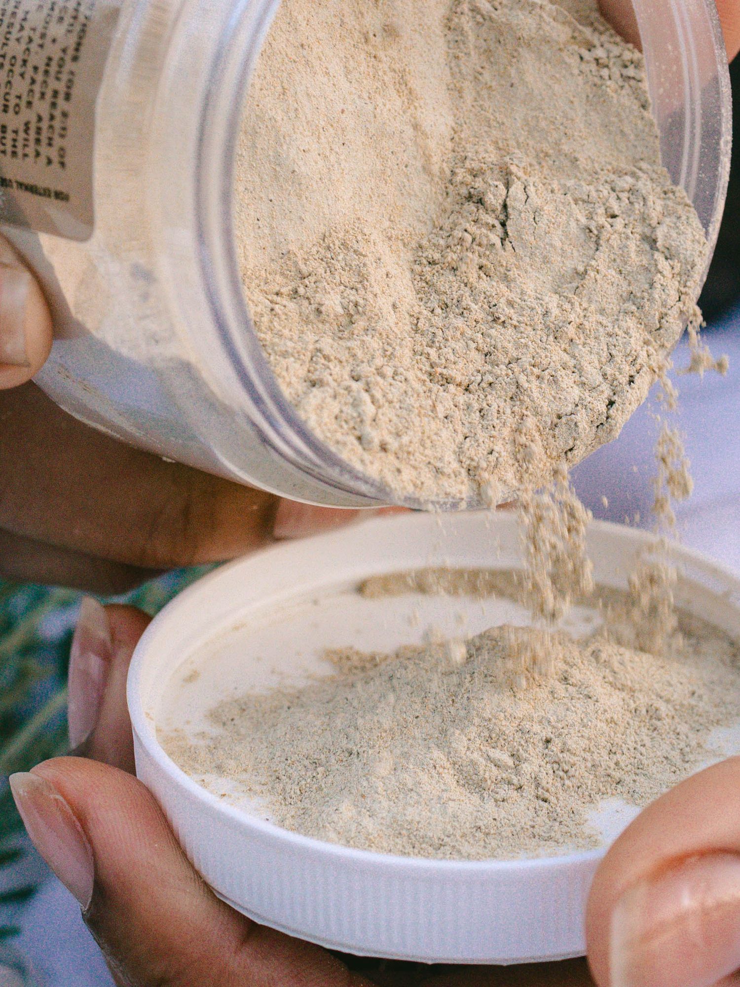 Close-up macro shot of powdered skin care falling into lid, showing fluffy, soft texture of powder product.