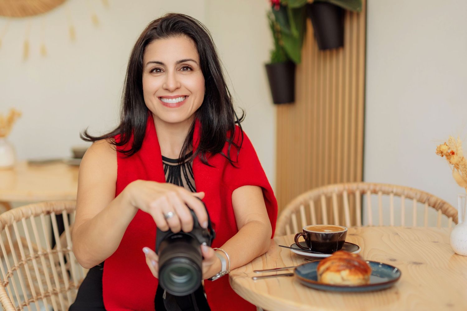 Lola Garcia,  the photographer behind Alba del Sol, seated in a cafe in London holding her camera with a red top