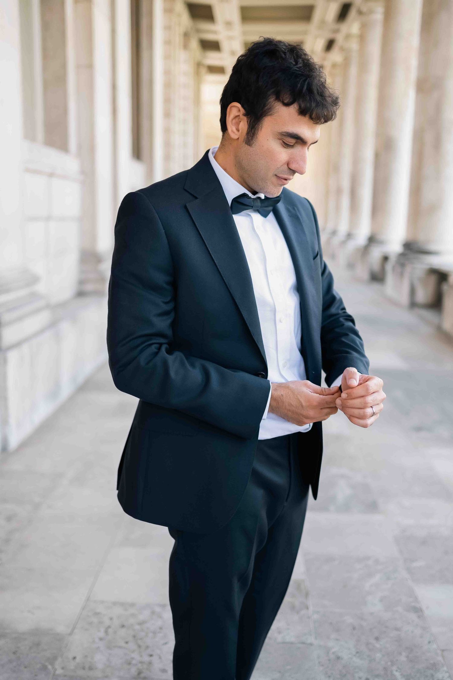 Elegant groom posing at the Old Royal College in Greenwich adjusting his cuff