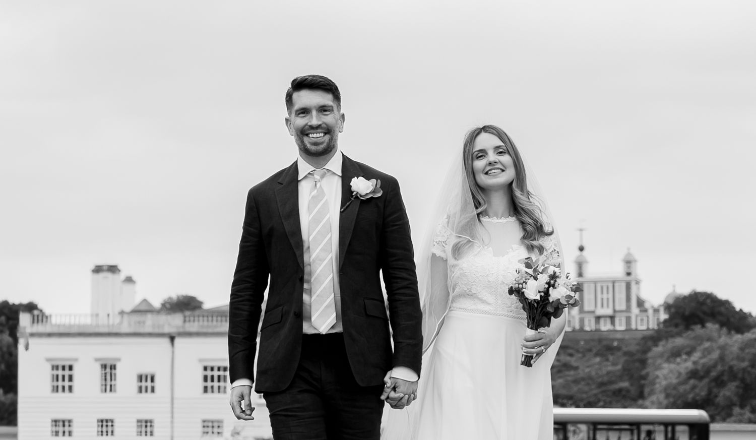 Newlyweds walking hand in hand outside the Queen’s House, with the Royal Observatory visible in the background by Alba del Sol Weddings