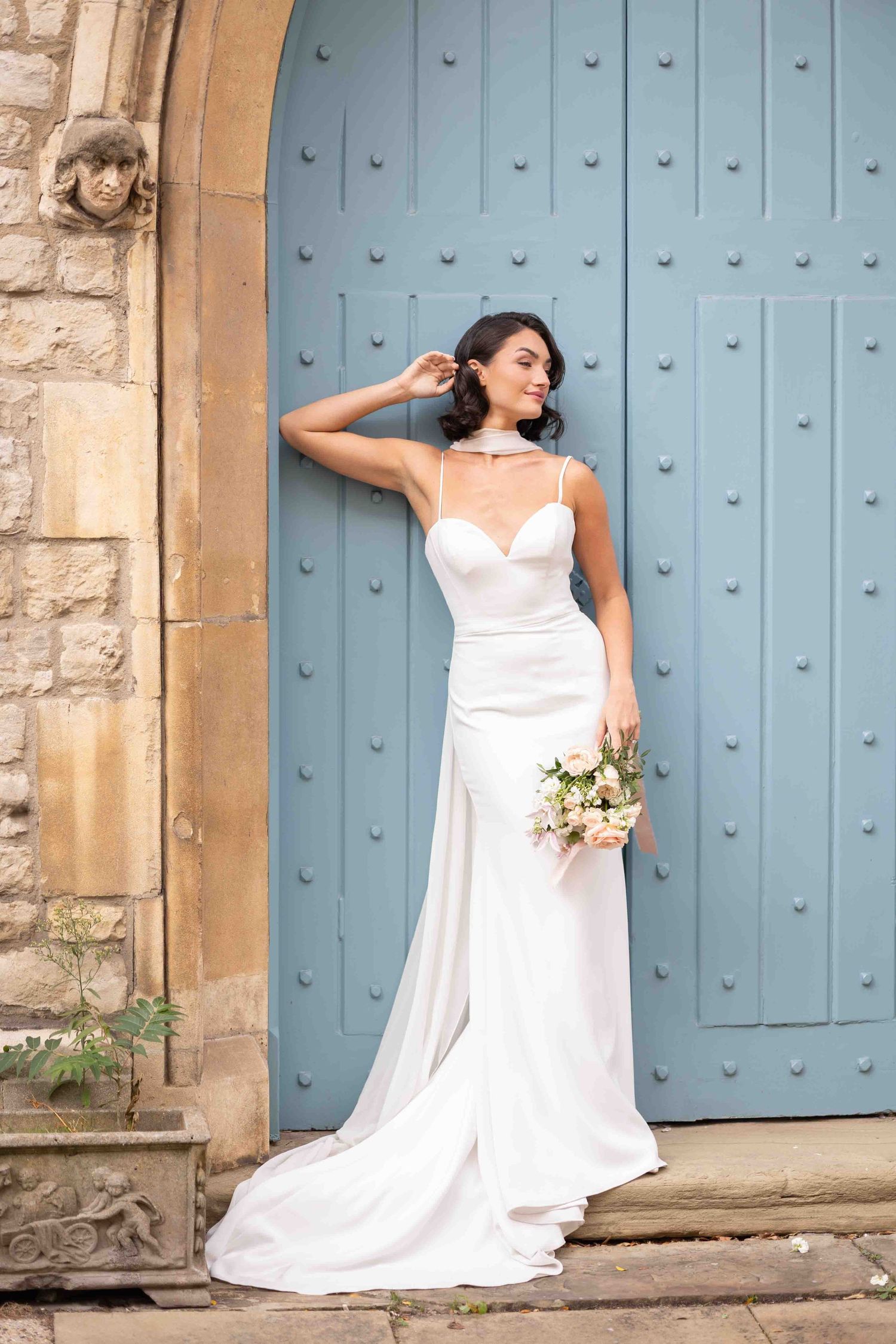 Elegant bride posing with her bouquet in a church with light blue door in Belgravia, luxury wedding photography by Alba del Sol.