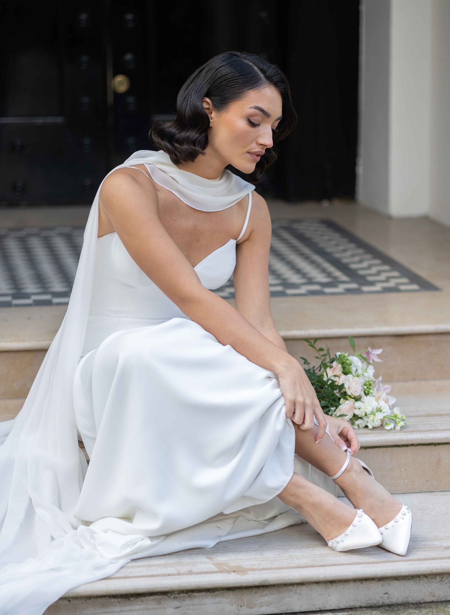Elegant bride seated on the floor in Belgravia adjusting her wedding shoes, photo by Alba del Sol wedding photography