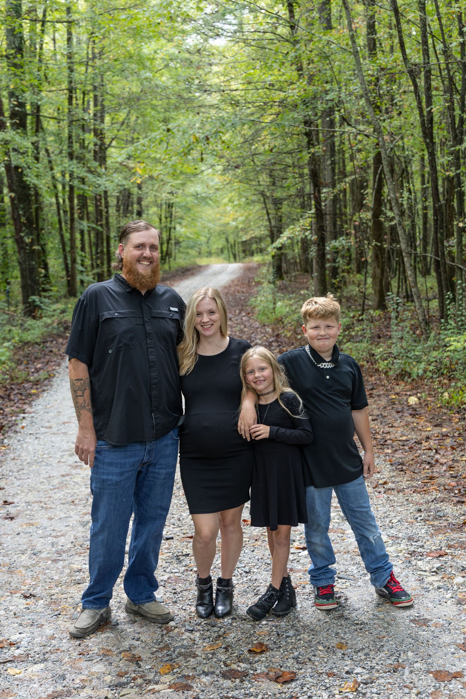Man, woman and children taking a family photo dressed in black and in the forest