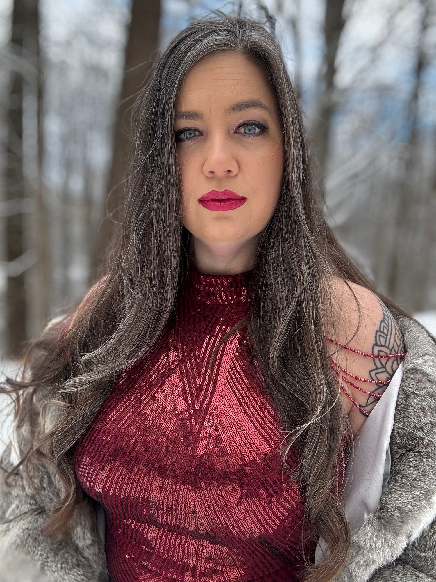 Portrait of a beautiful woman in red with snowy trees in the background
