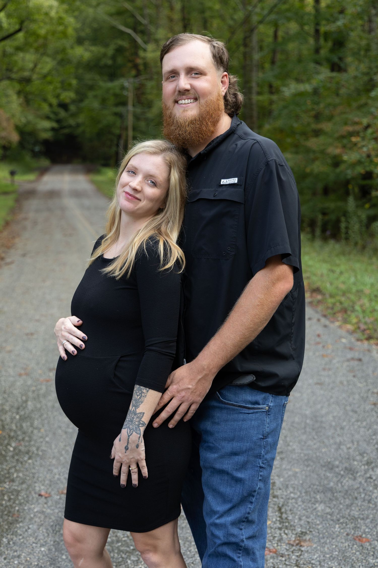 Man and woman hugging and holding each other down a forest road